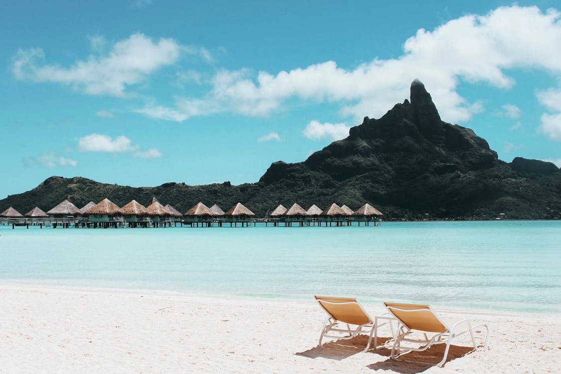 Chairs on a beach with huts on the water