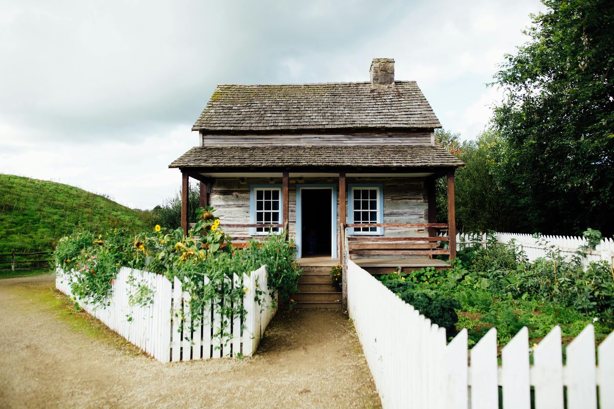A log cabin with a white fence