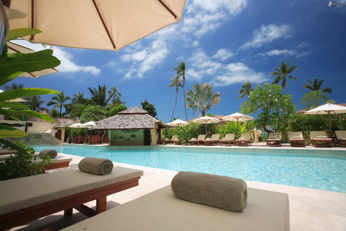 A swimming pool with lounge chairs and umbrellas