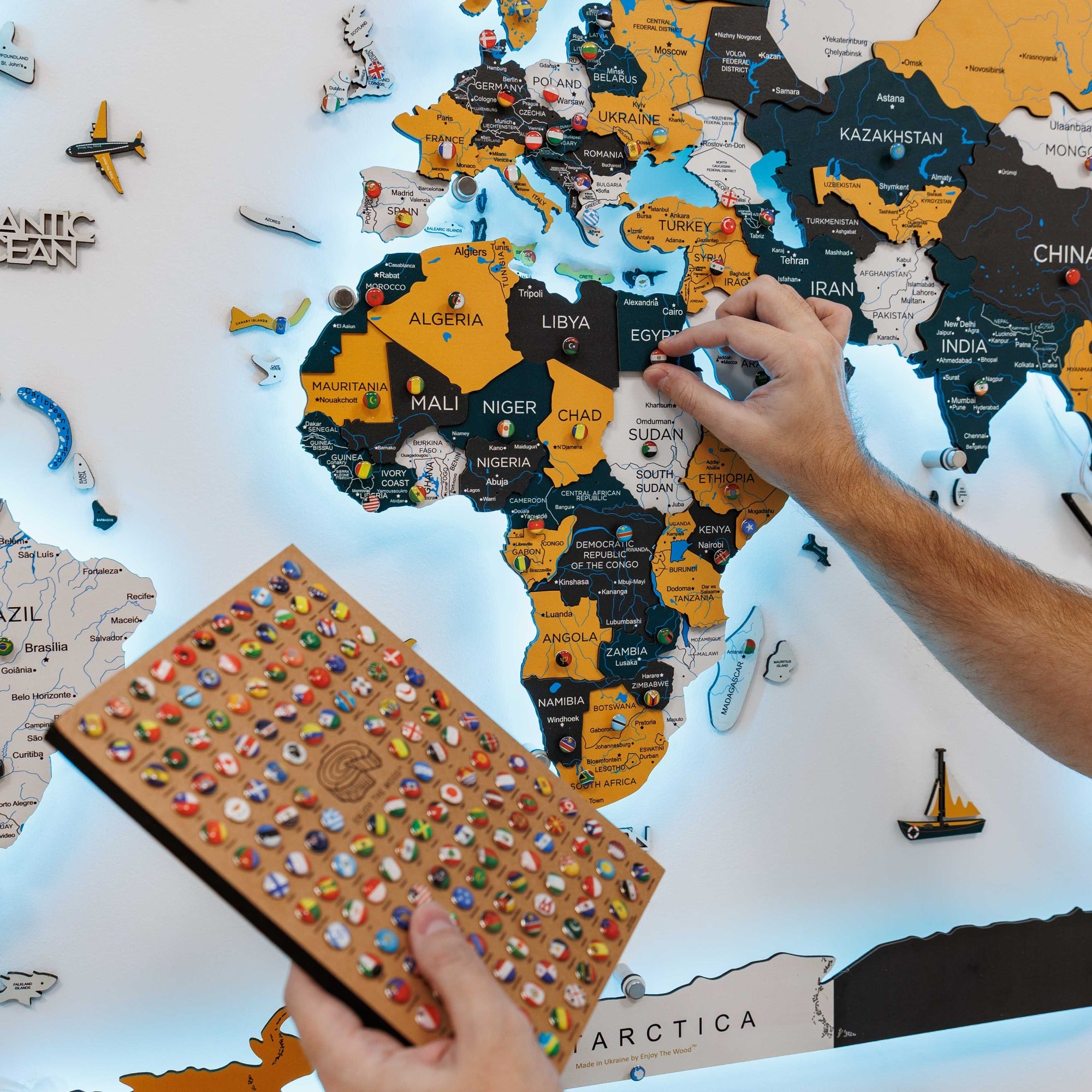 Person assembling a world map puzzle on a white surface