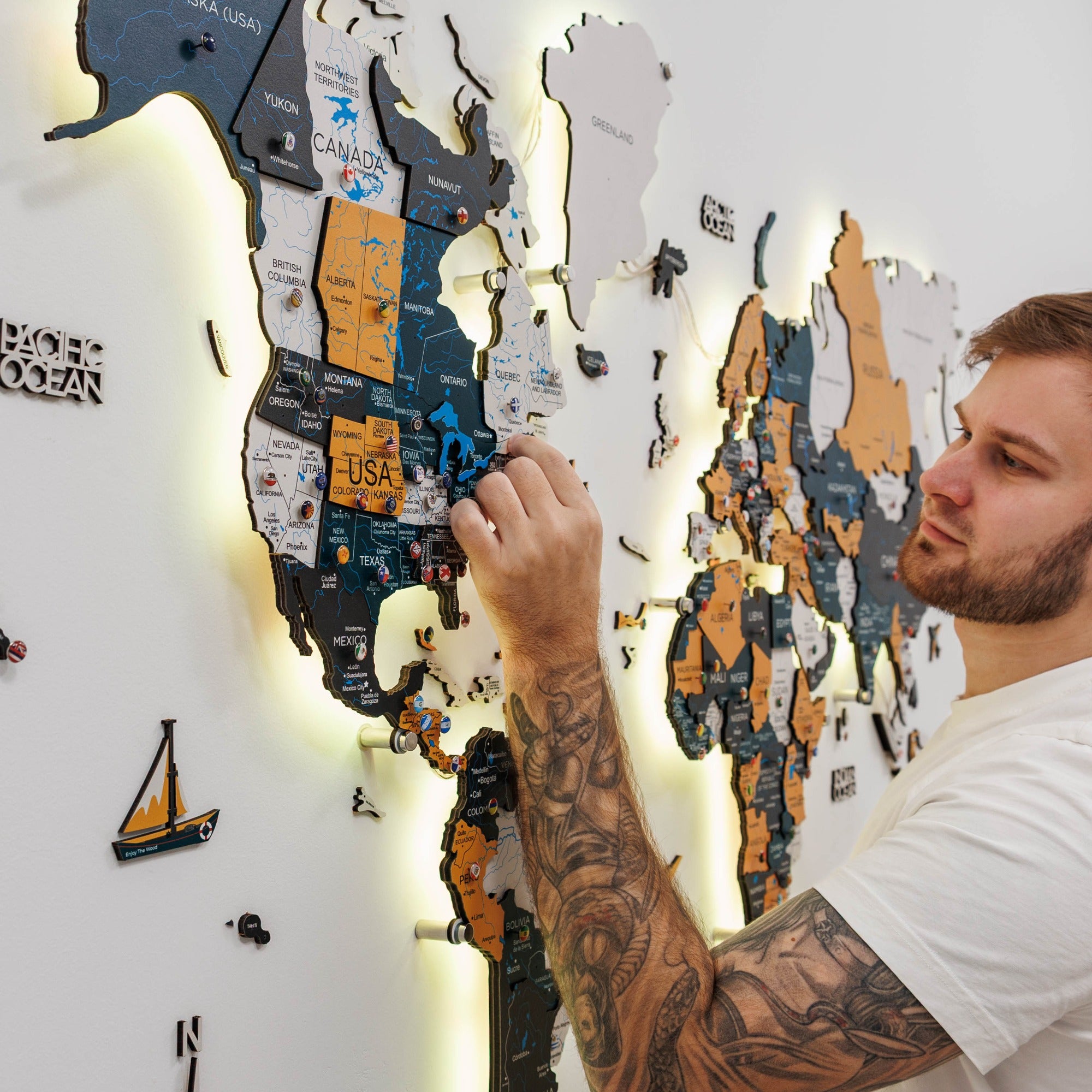 Man interacting with a wall-mounted map of North America with illuminated edges.