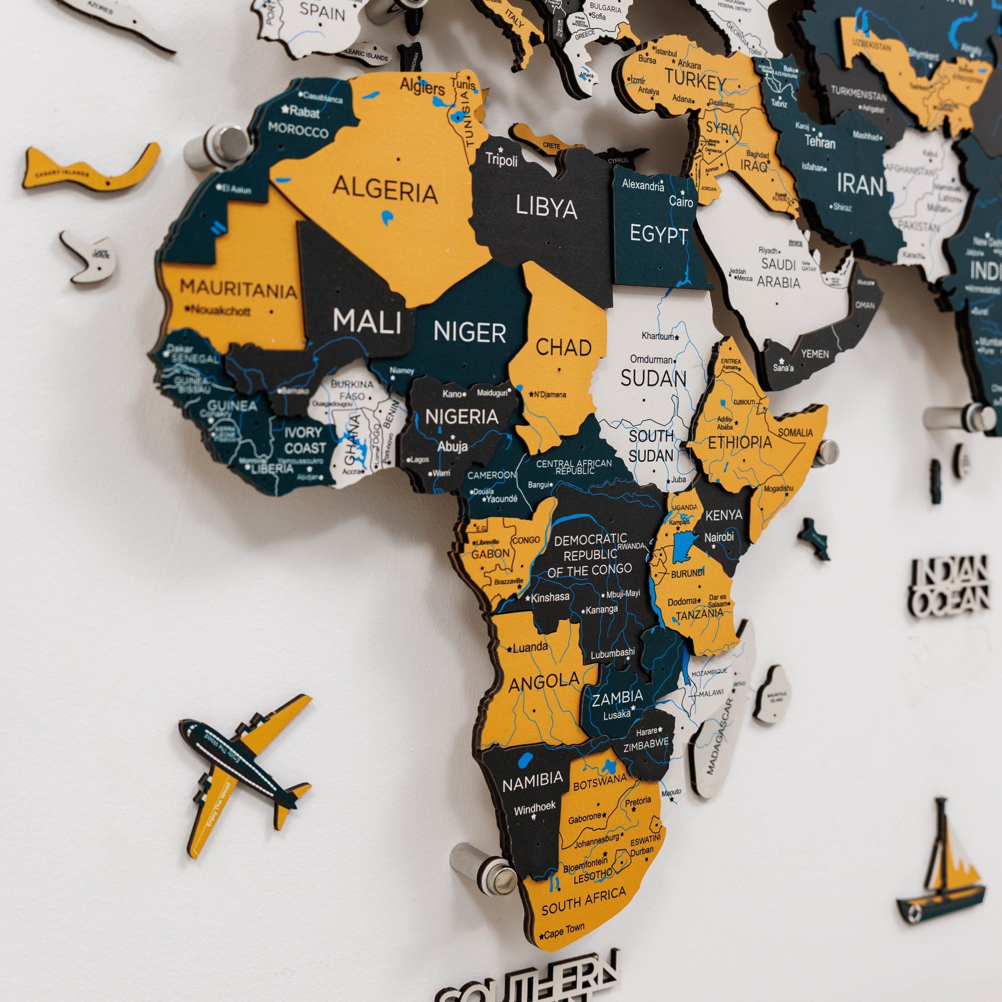 Wooden map of Africa with country names and a small airplane model on a white background