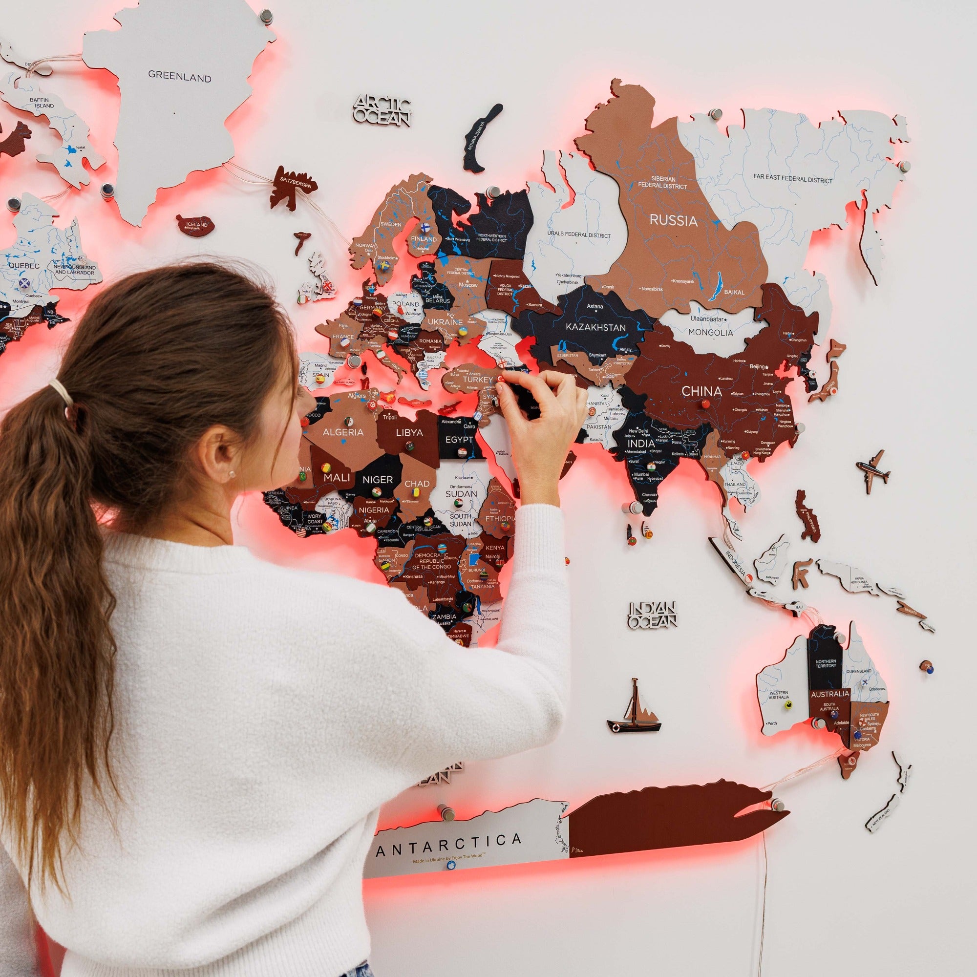 Woman assembling a puzzle of a world map with illuminated edges.