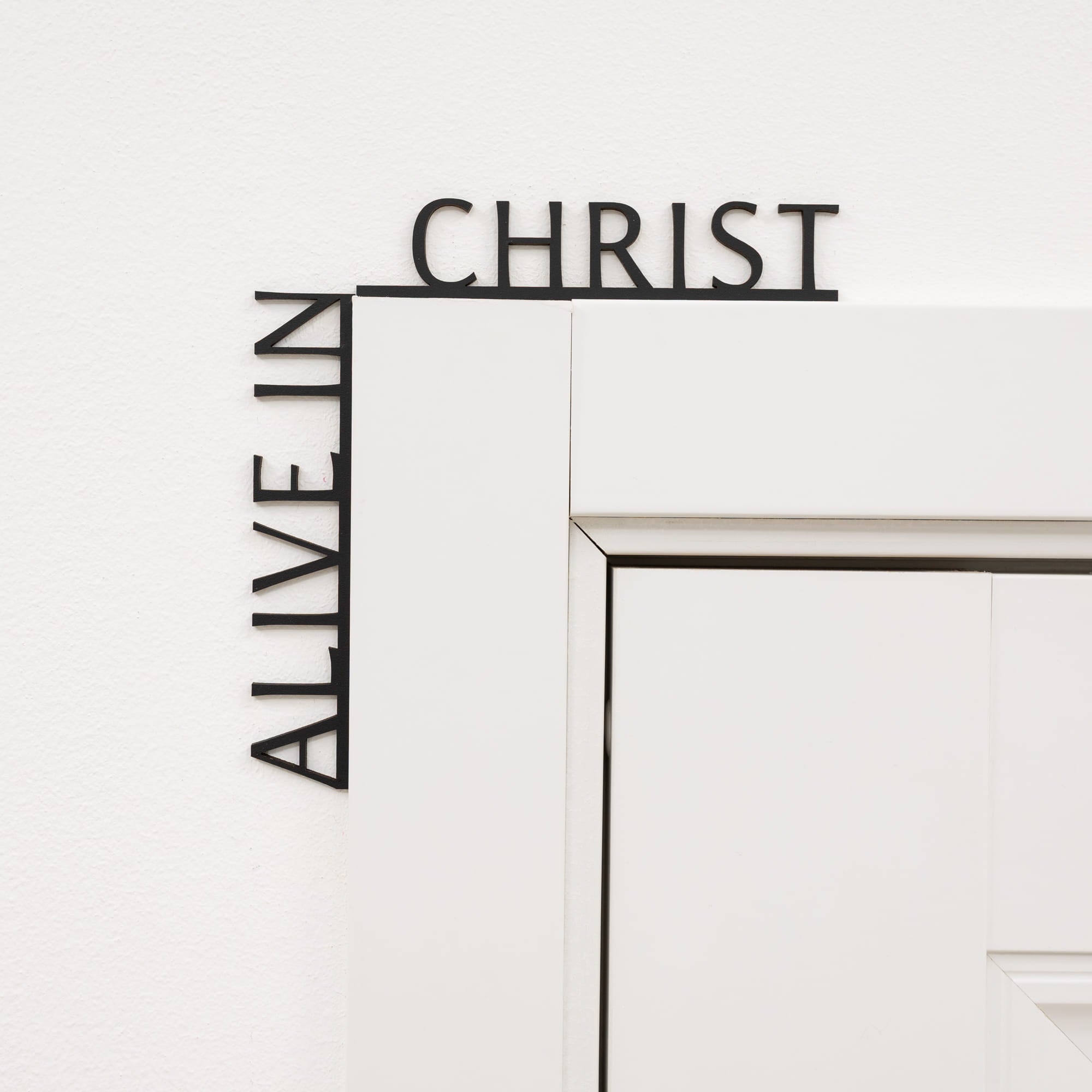 Decorative wall art with 'Alive in Christ' text on a white background