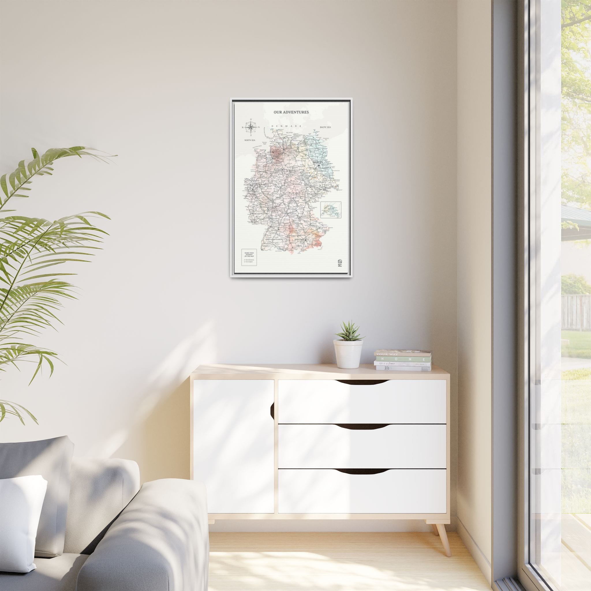 Modern interior with a white dresser, framed map, and a plant.