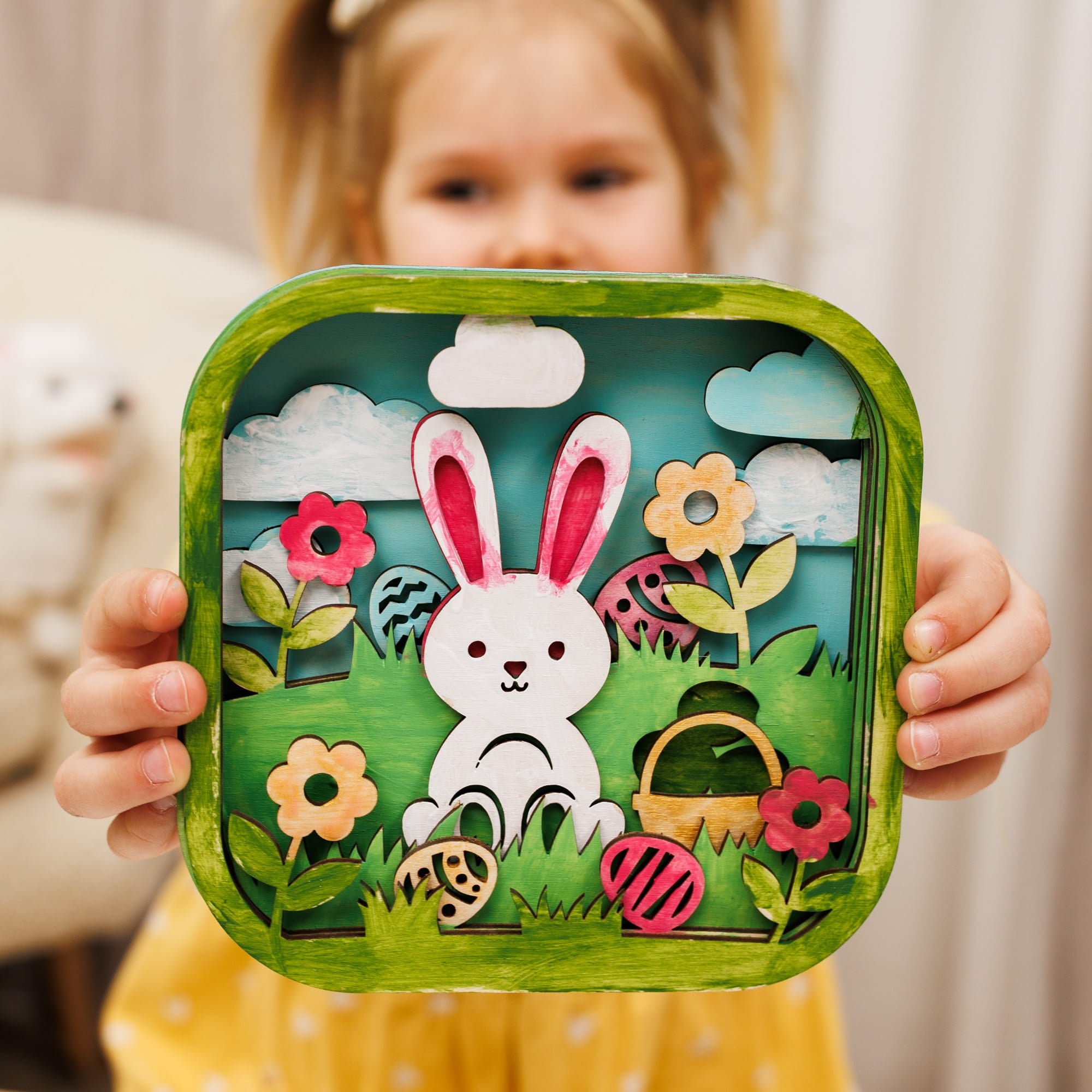 Child holding a decorative Easter-themed box with a rabbit design.