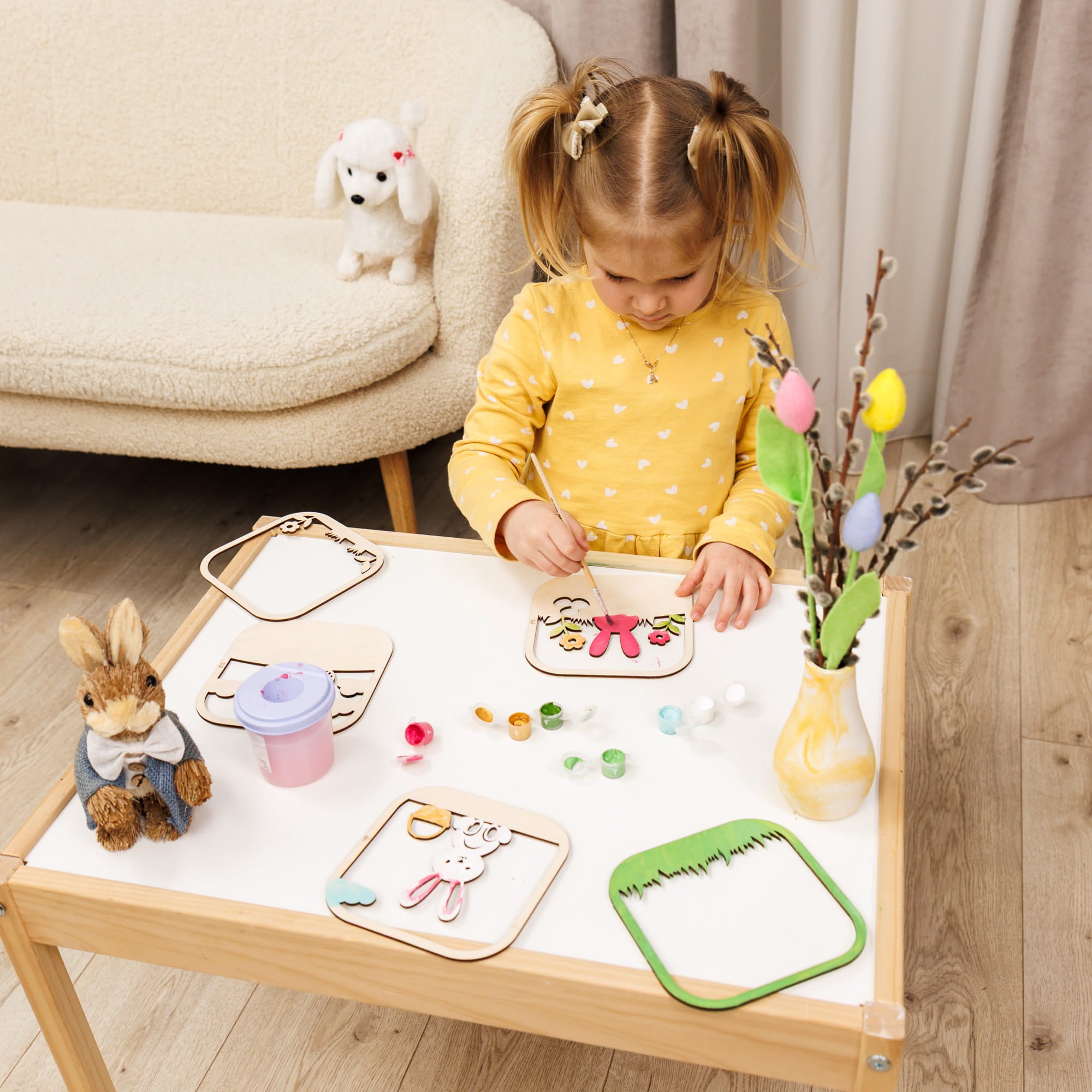 Child engaged in craft activity at a table with various materials and toys.