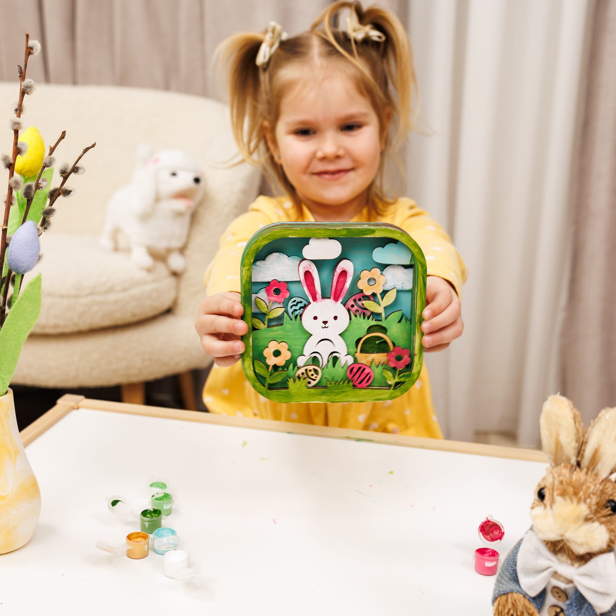 Child holding a decorative Easter tin with a rabbit design, surrounded by Easter decorations.
