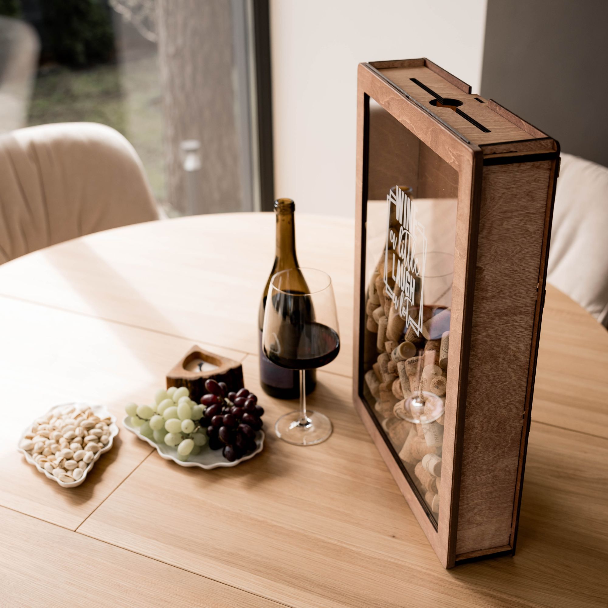 Wine cork display box with glass of wine, bottle, grapes, and nuts on table
