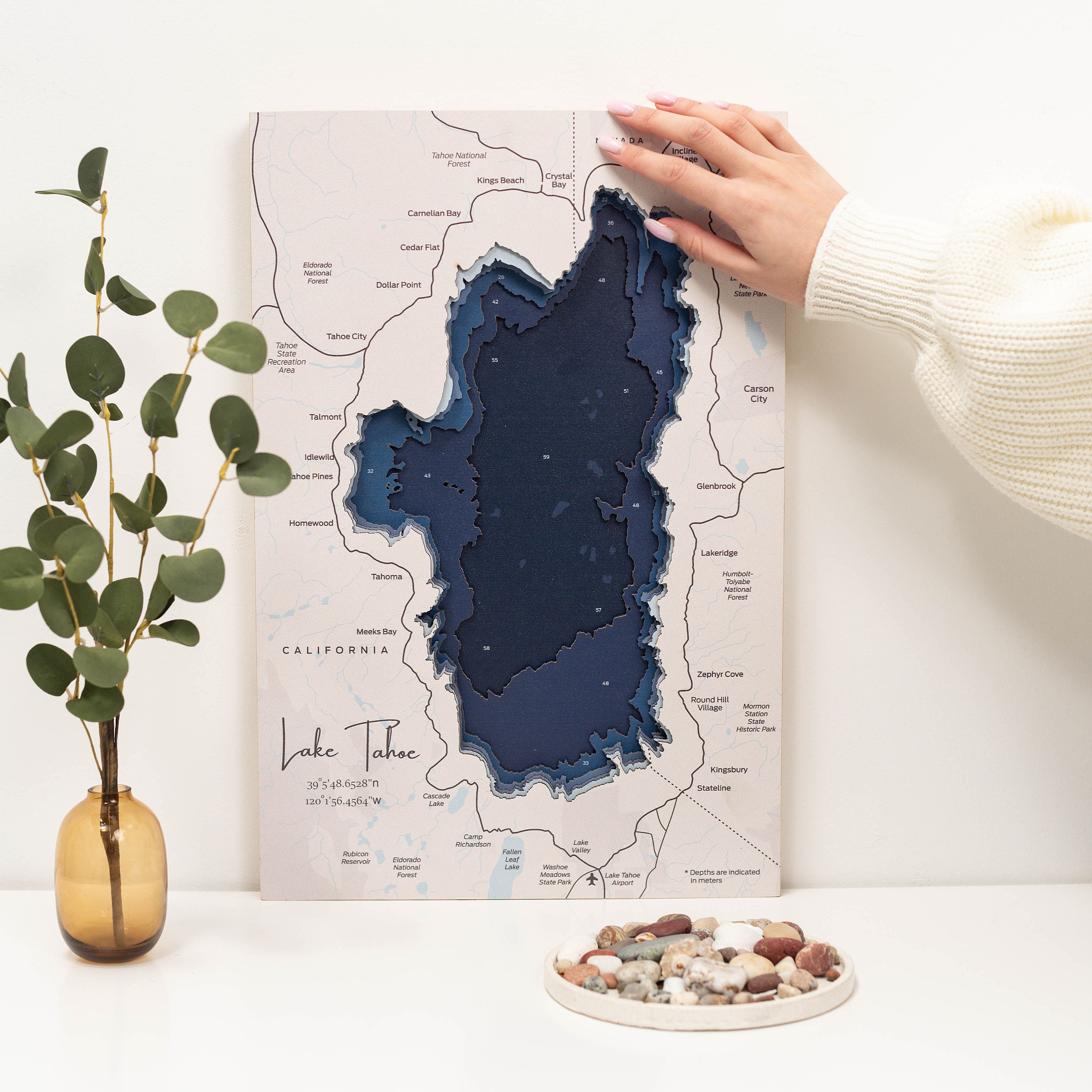 Map of Lake Tahoe with a hand pointing to it on a white surface.