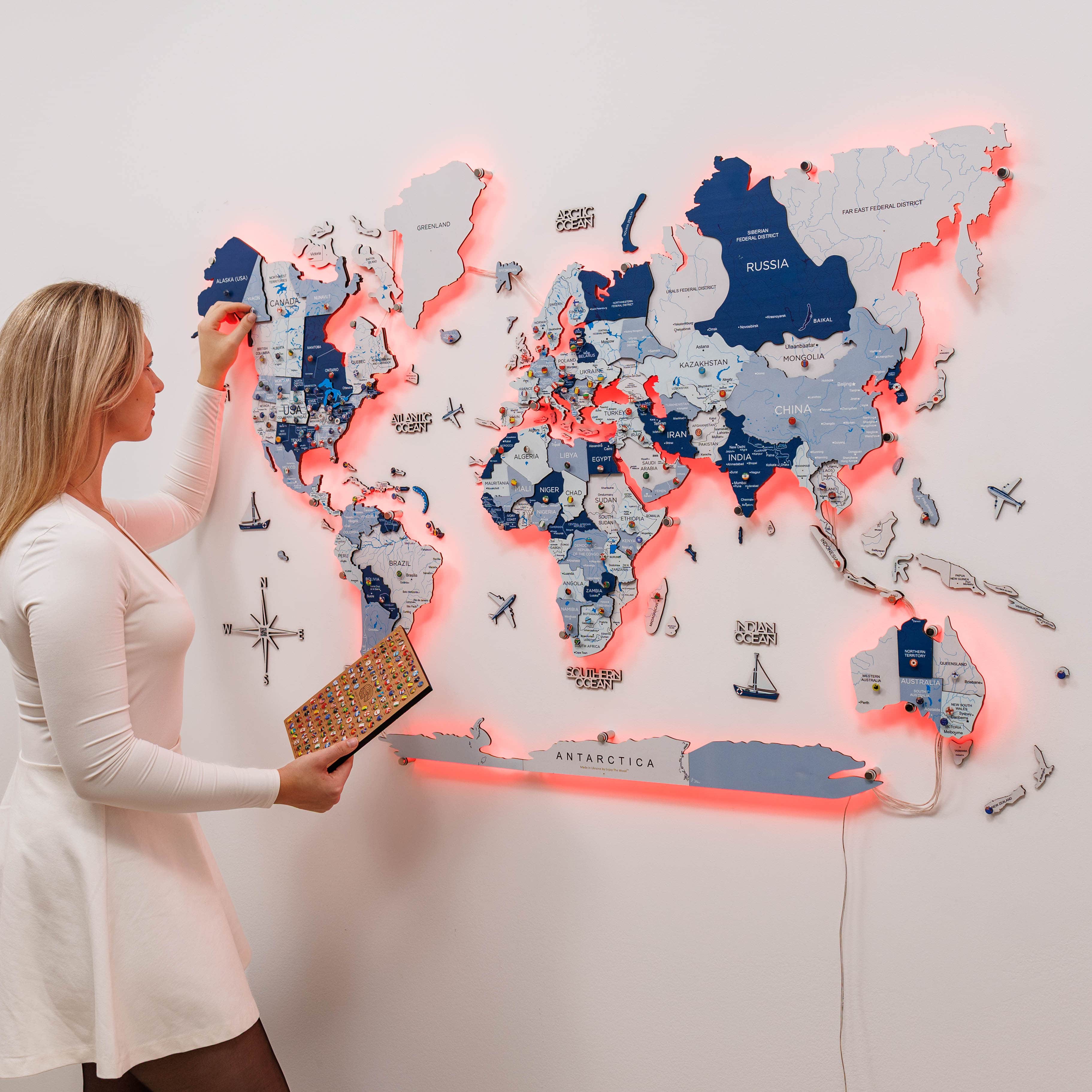 Woman interacting with a world map light board on a white wall