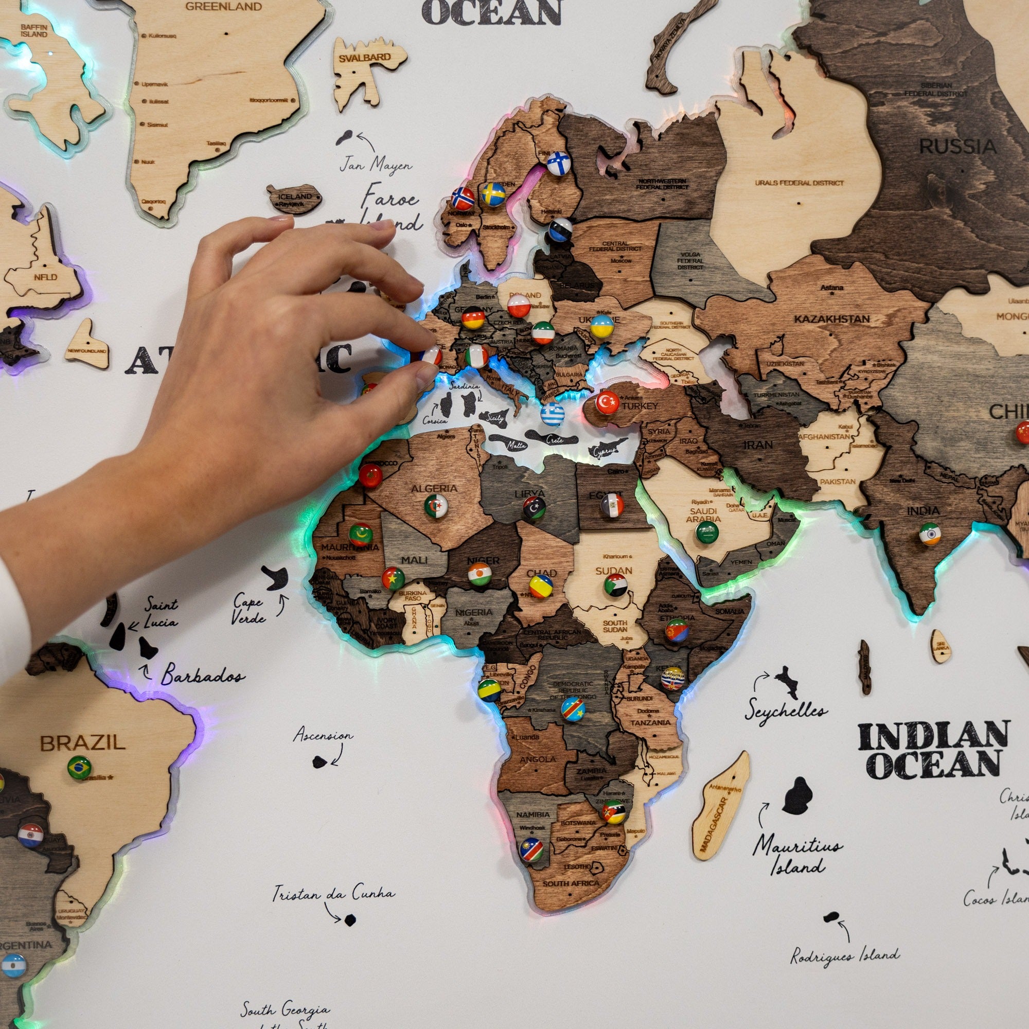 Wooden world map with colorful pins and a hand interacting with it