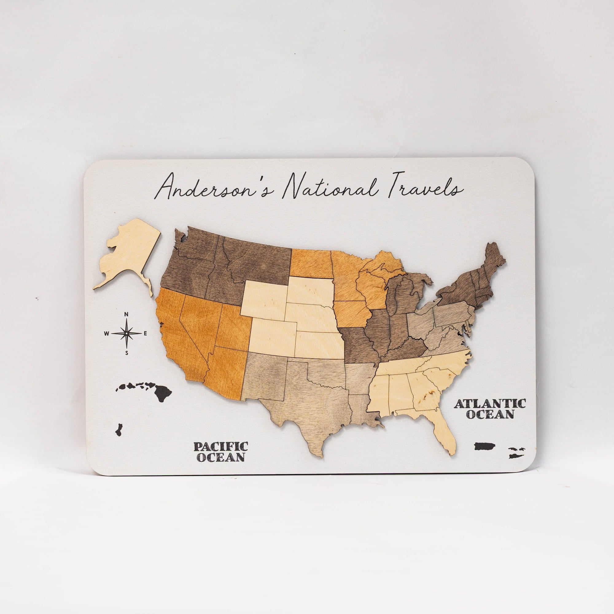 A wooden US state travel map plaque titled 'Anderson's National Travel' on a white background. The map features states in various natural wood tones from light beige to dark brown, with the Pacific and Atlantic Oceans labeled.