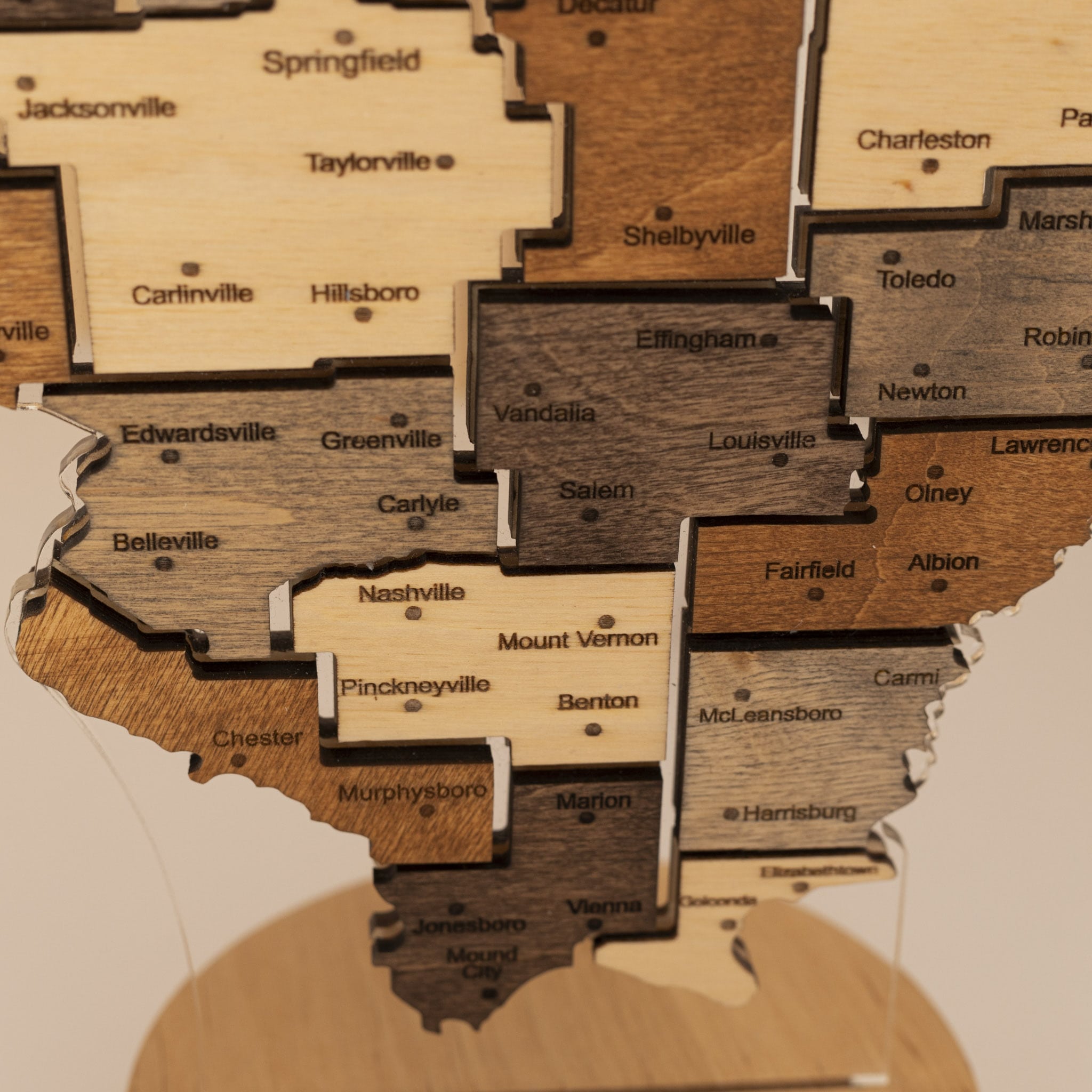 Wooden map of Illinois with cities labeled on a beige background