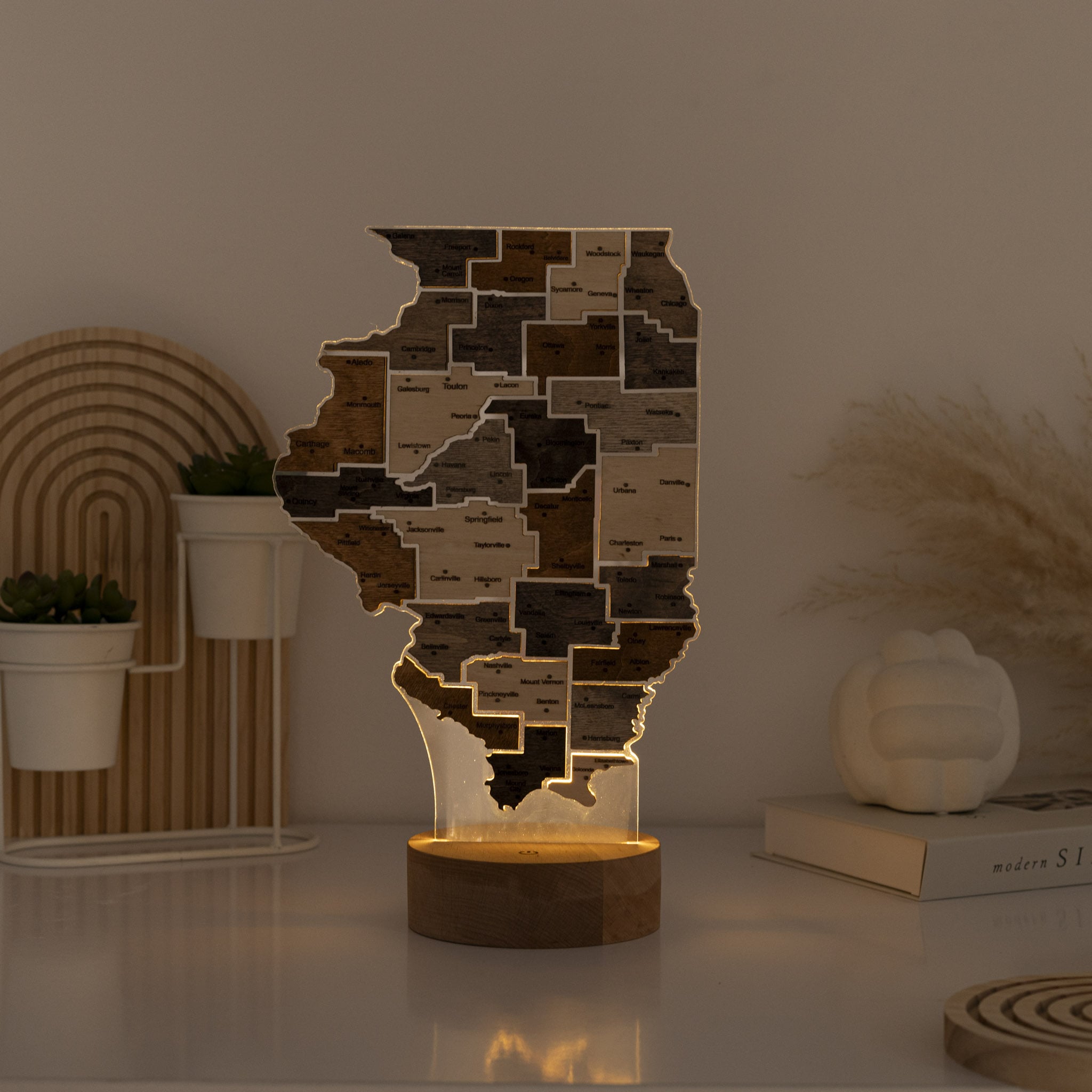 Wooden lamp shaped like a state with a warm glow on a table.