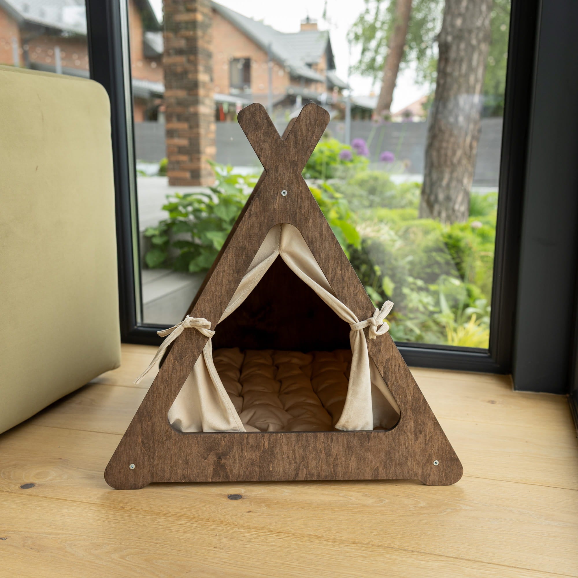 Wooden pet teepee with beige interior on a wooden floor, outdoors.