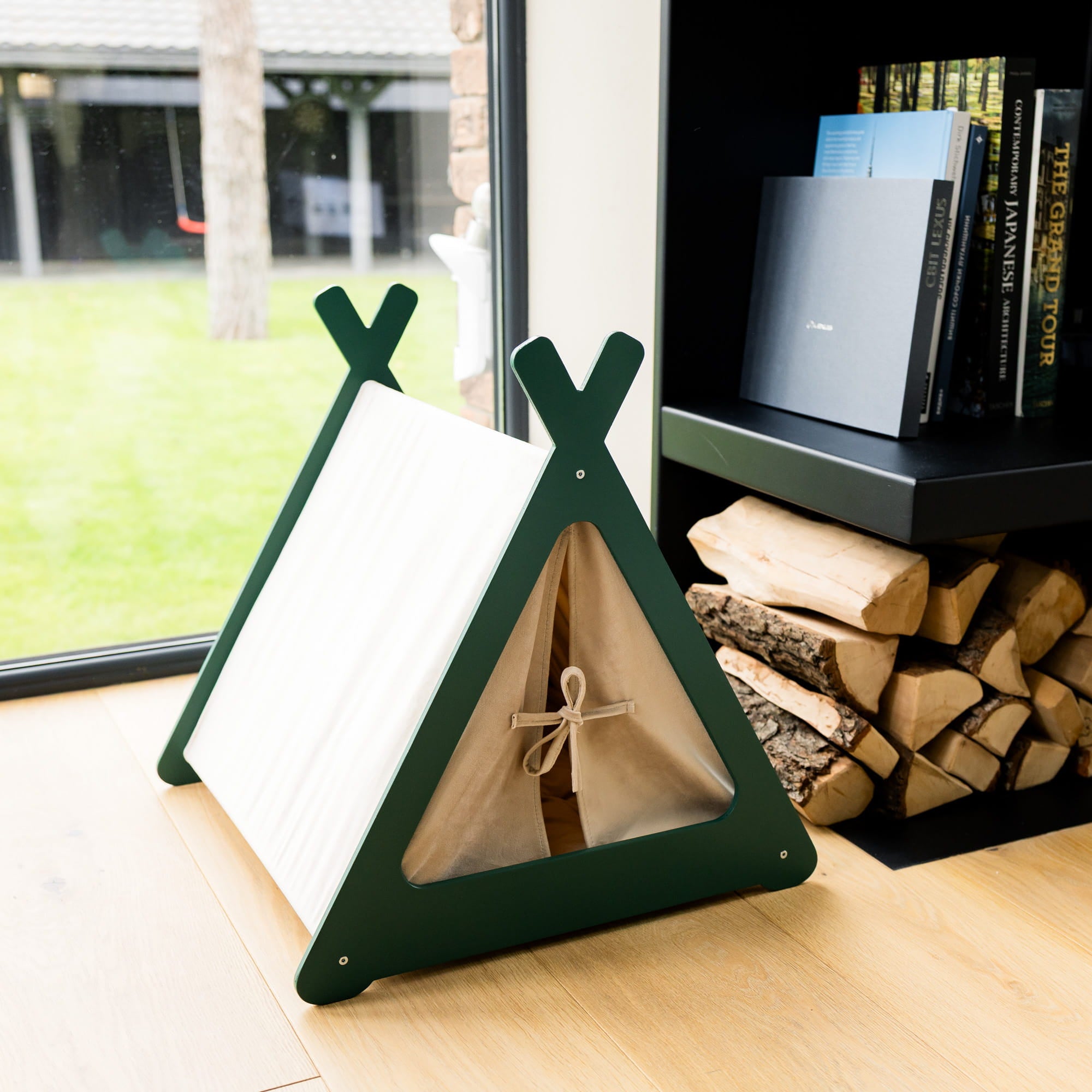 Wooden teepee toy on a wooden floor with books and firewood in the background