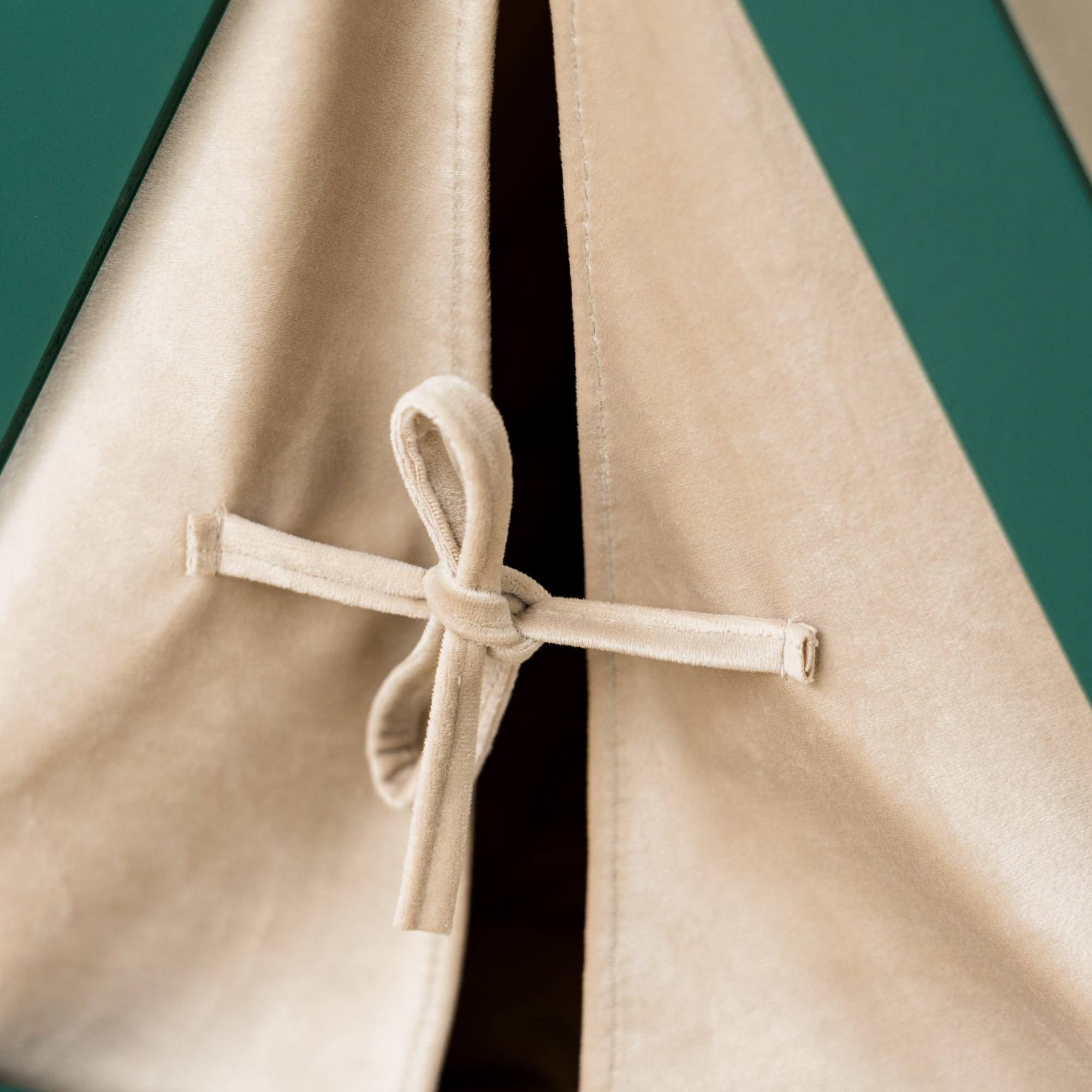 Close-up of a beige coat with a button detail on a dark green background