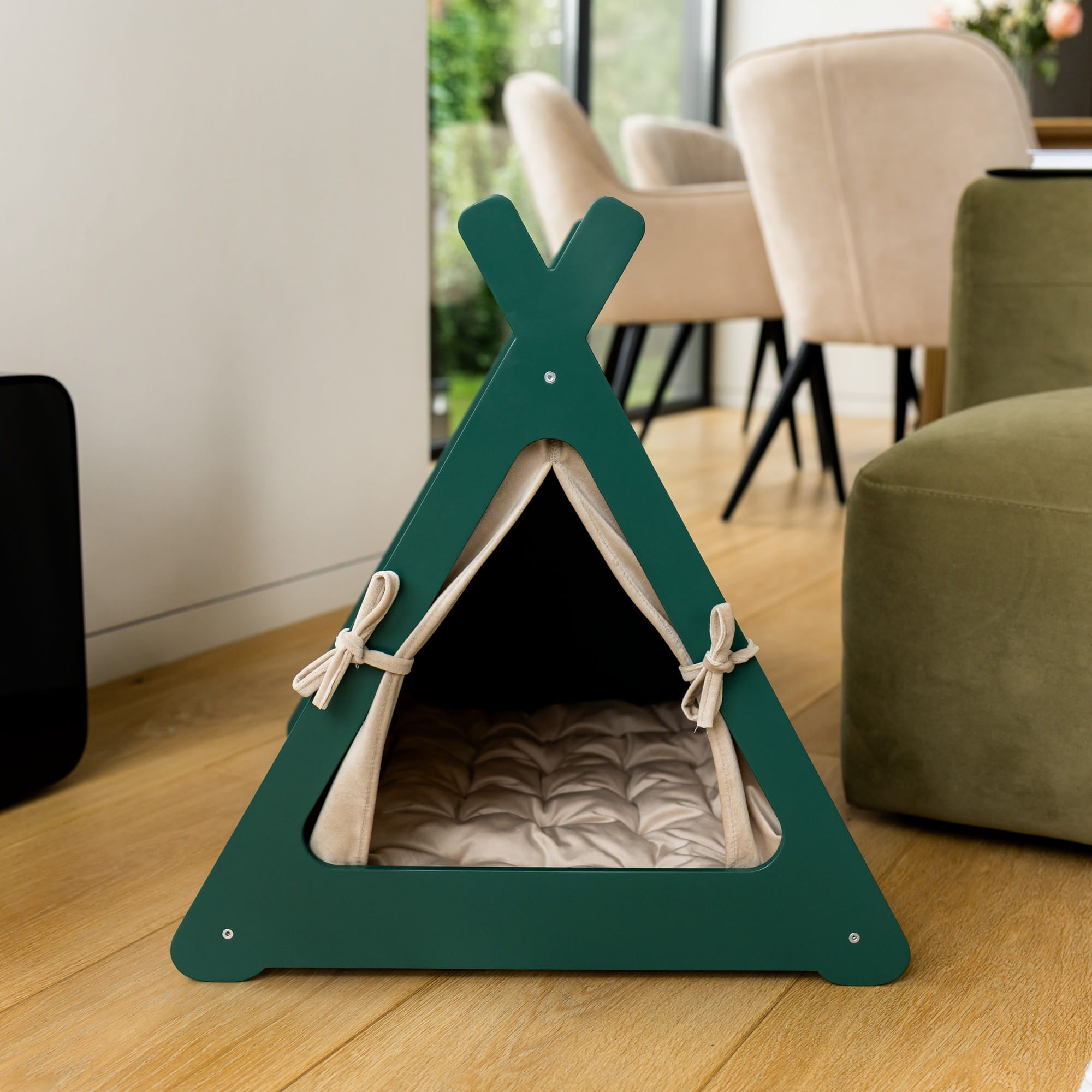Green pet teepee on a wooden floor with a blurred background