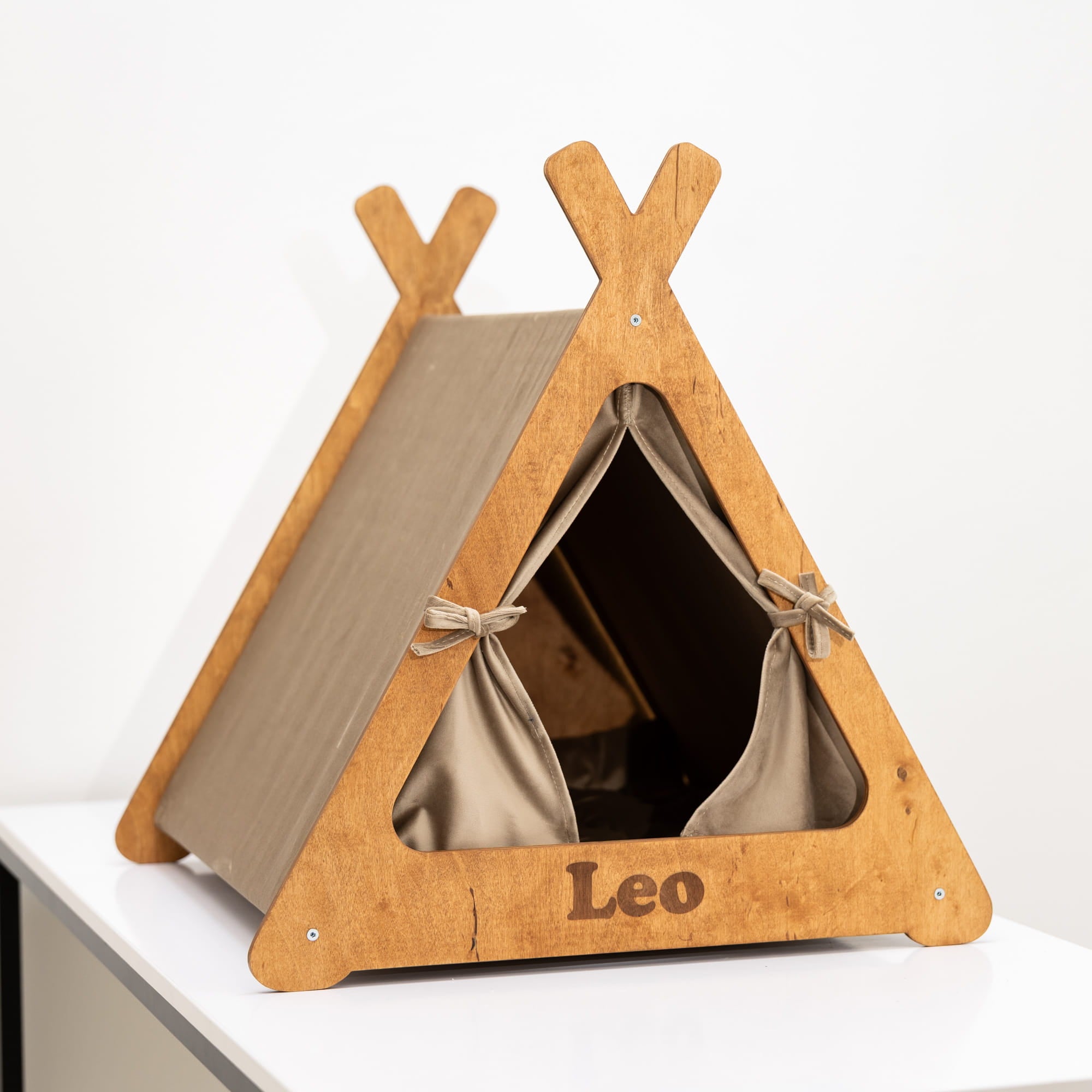 Wooden pet teepee with beige interior on a white surface