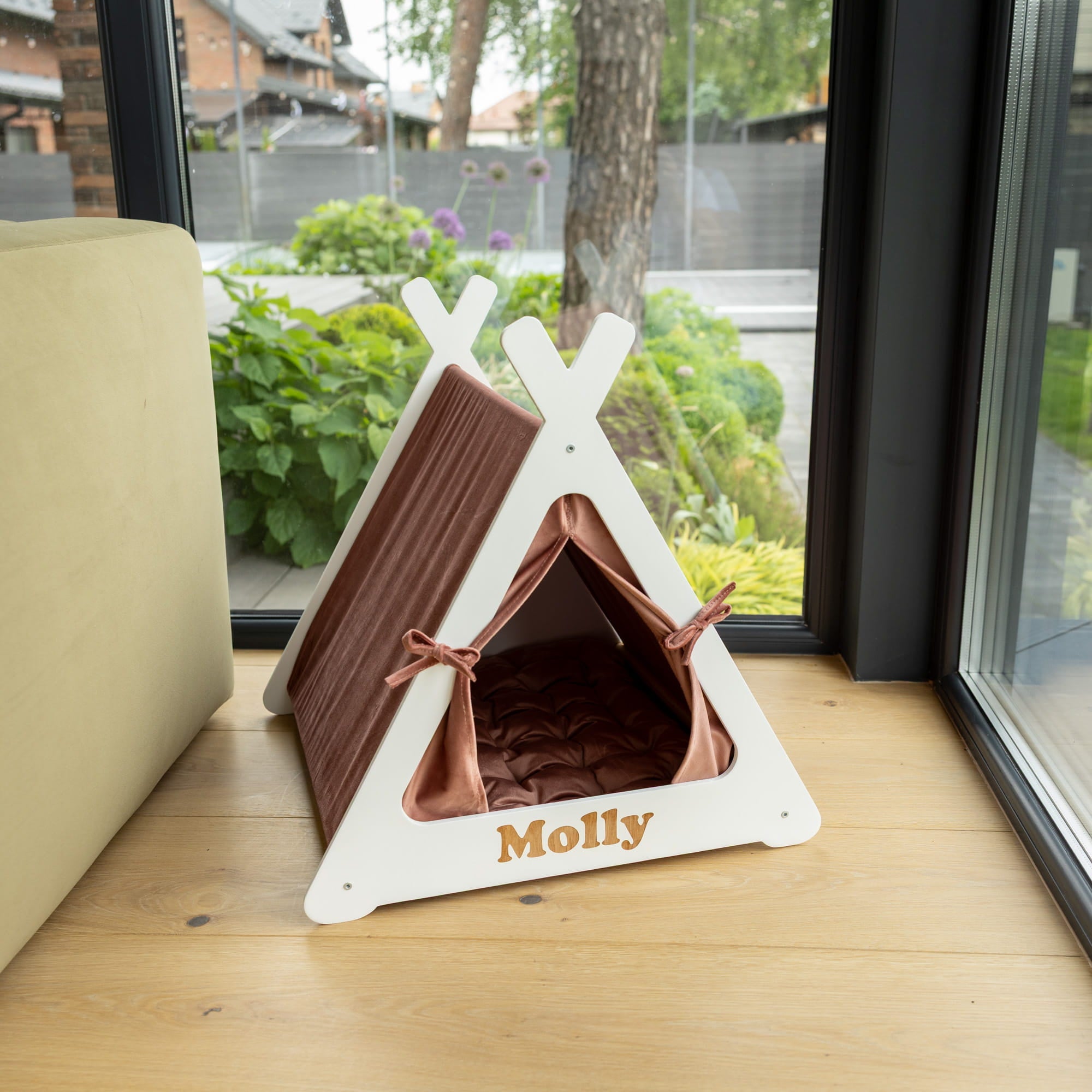 Pet teepee with brown interior and white exterior on a wooden surface near a window.