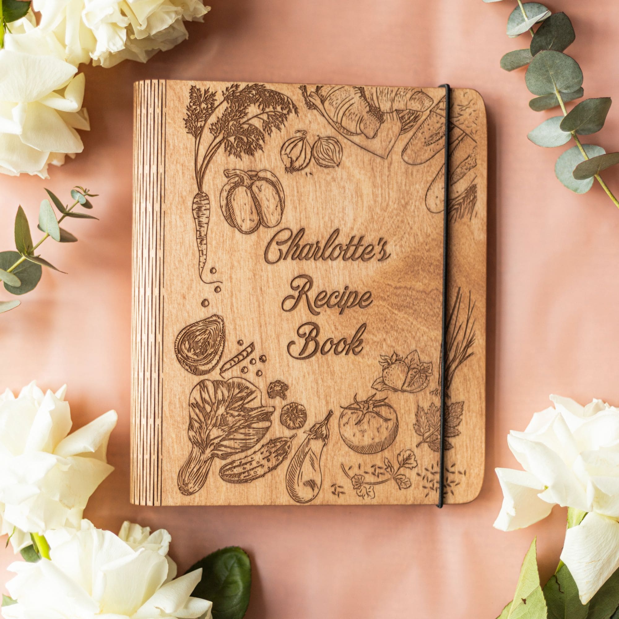 Handmade engraved recipe book surrounded by herbs and pasta ingredients