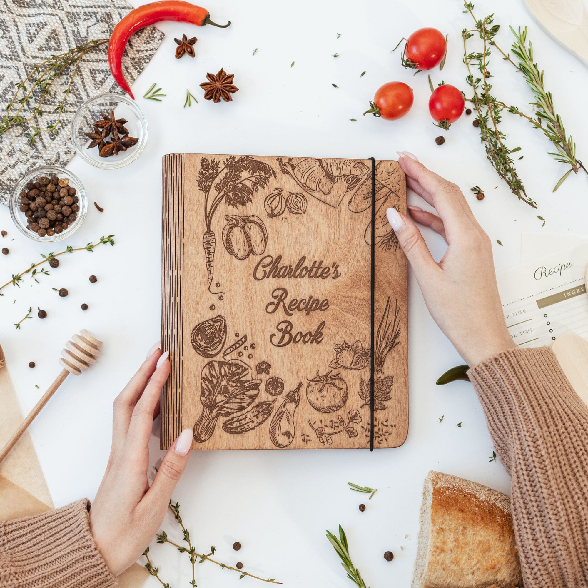Person holding engraved wooden recipe book with berries around