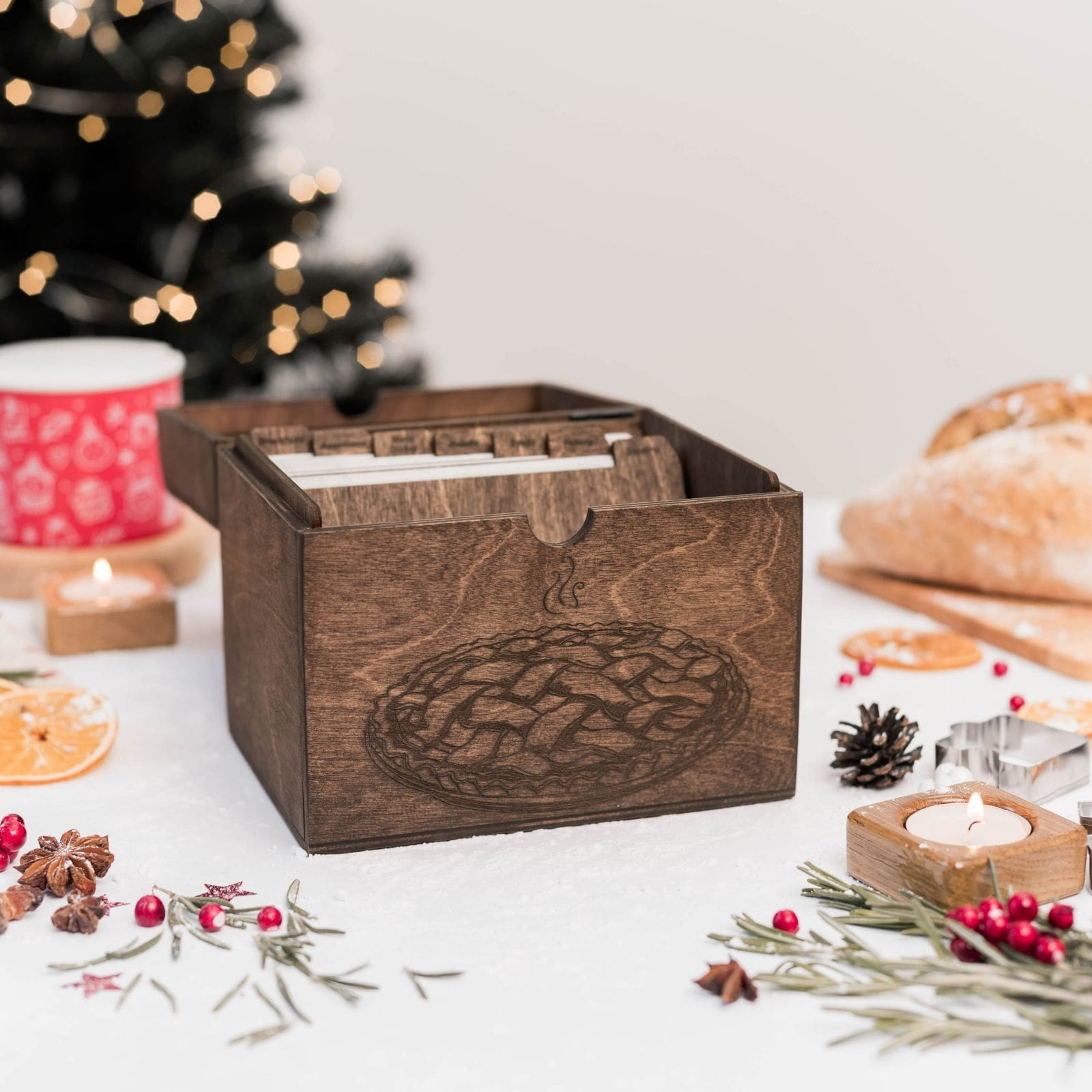 Open dark wooden recipe box filled with cards on decorated Christmas table.
