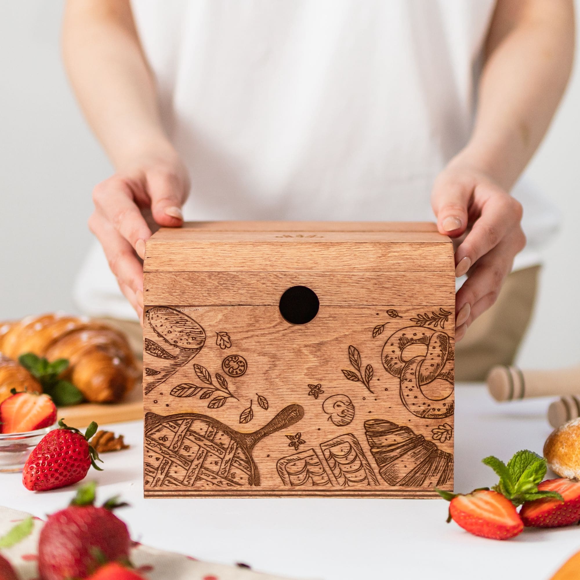 Closed engraved wooden recipe box for storing family recipes on kitchen table with strawberries