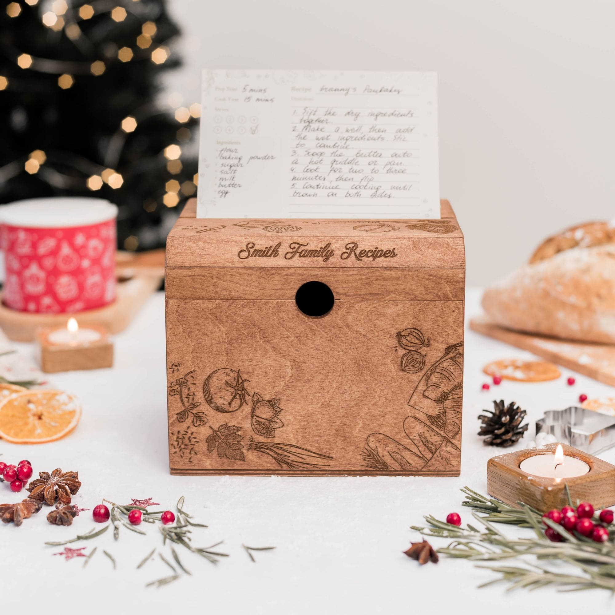 A wooden recipe box with pepper illustrations, placed on a table with festive decorations, displaying recipe cards inside.