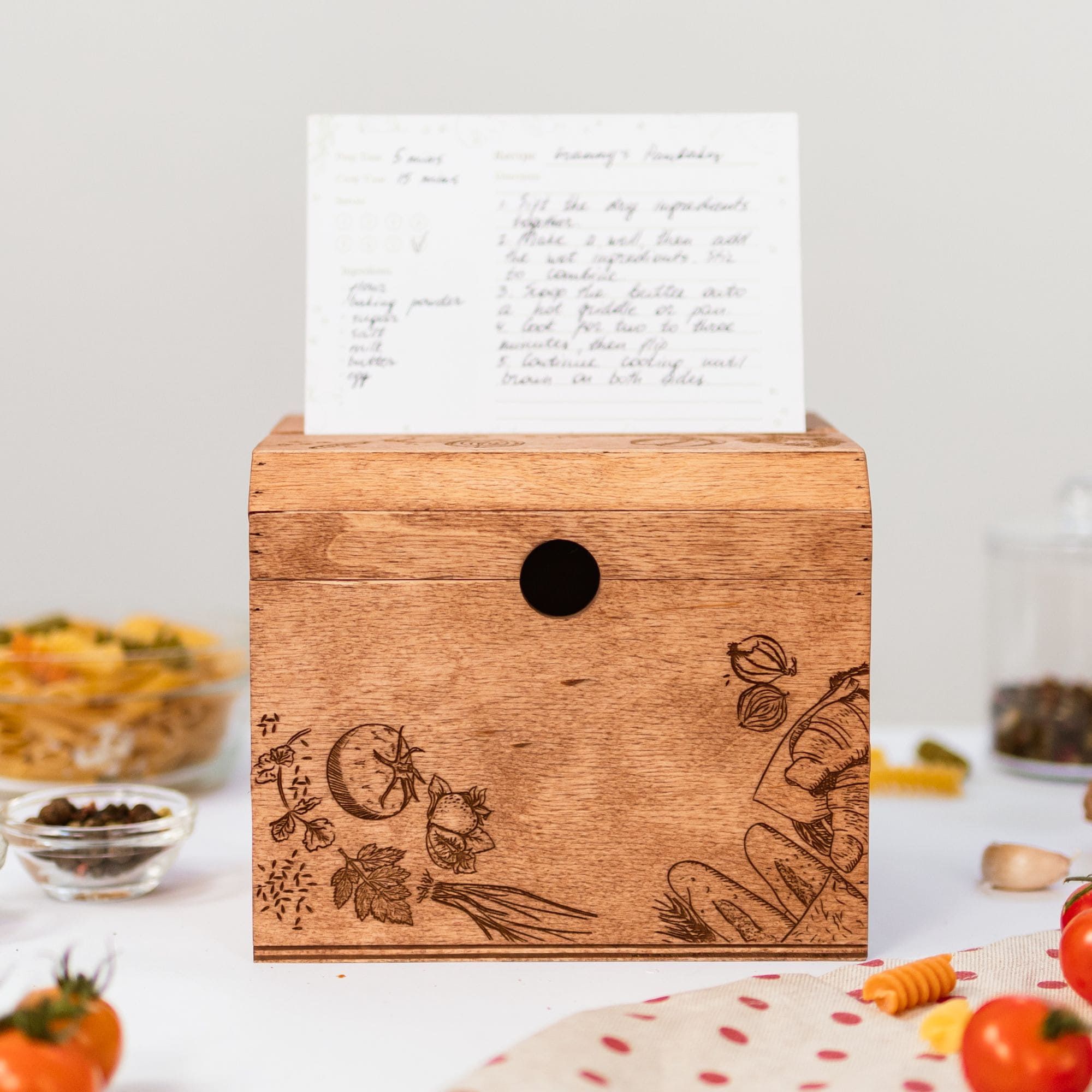 Closed wooden recipe box with engraved vegetables and recipe card standing on top