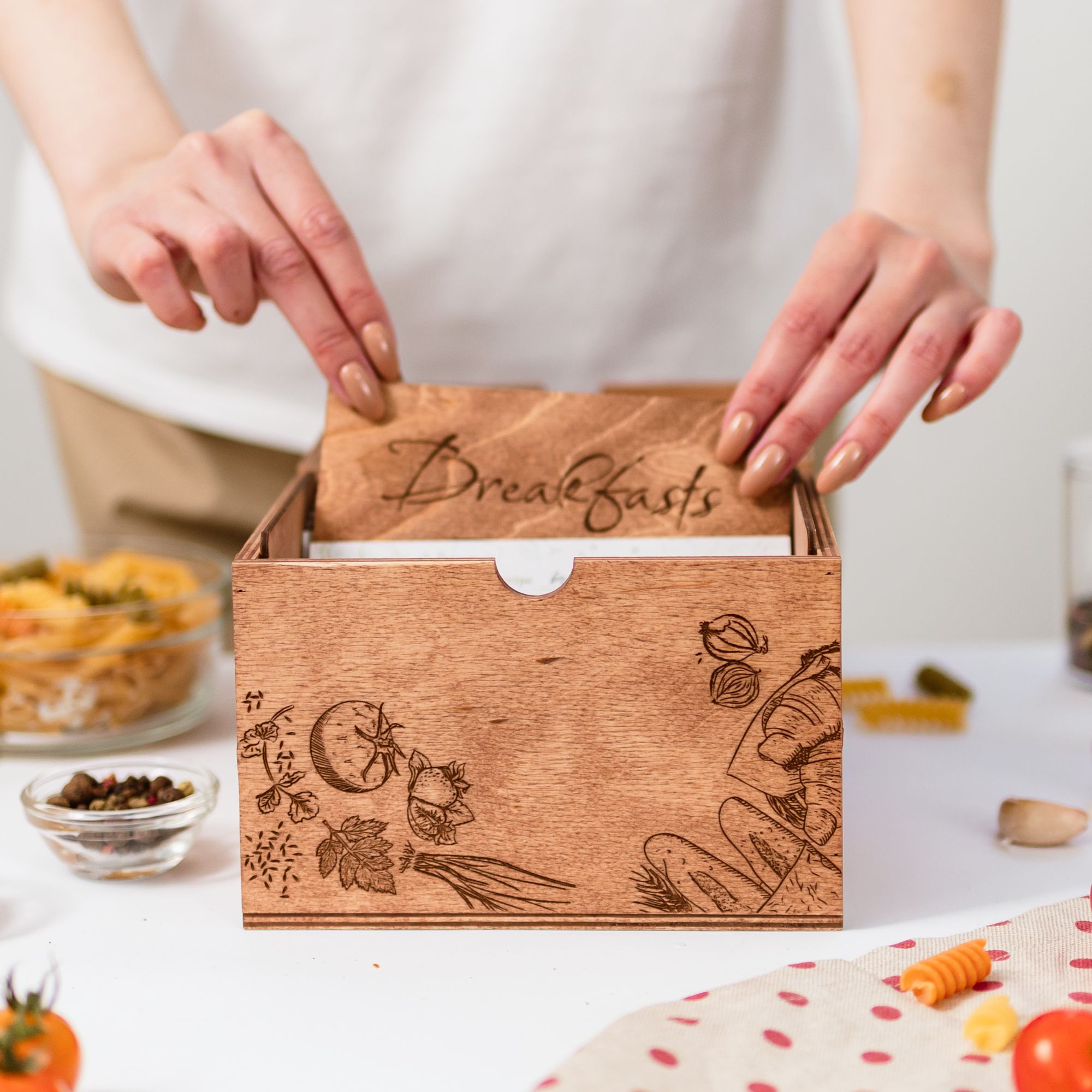 Hands placing breakfast divider card into wooden recipe box with engraving