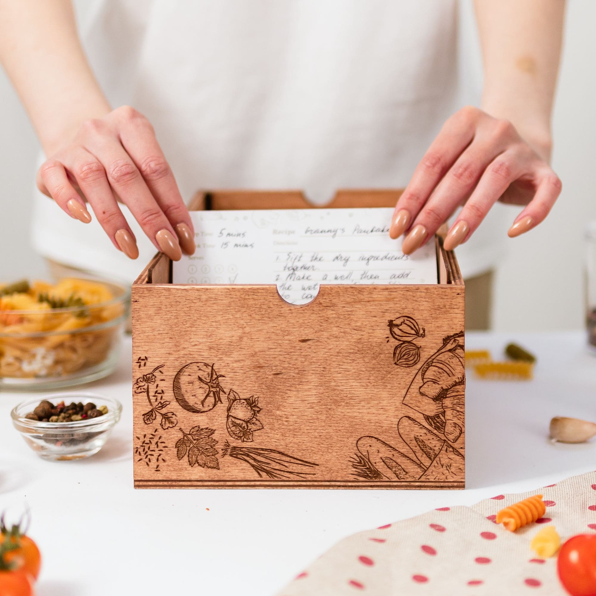 Wooden recipe box with engraved vegetables and handwritten recipe cards inside
