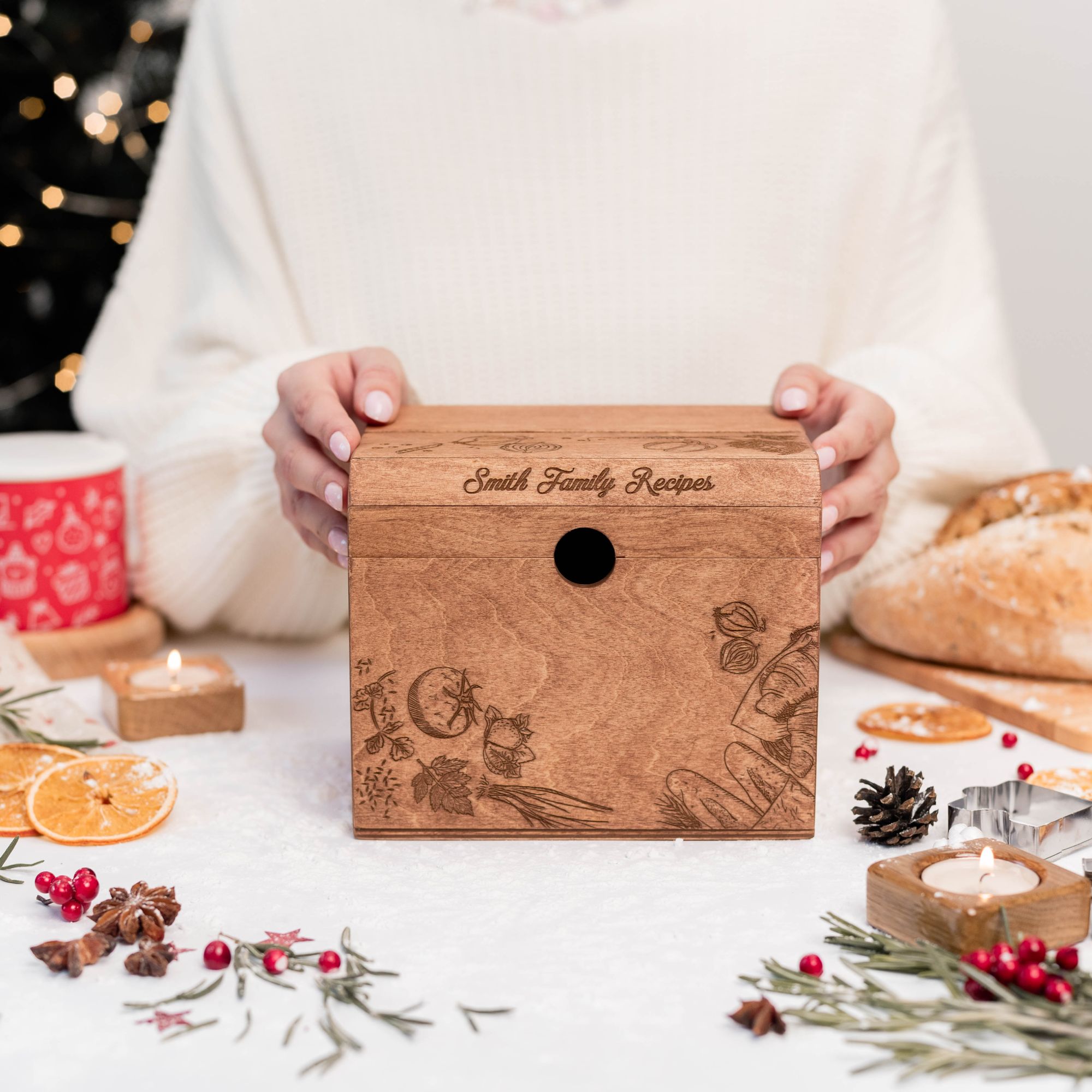 Hands holding personalized engraved wooden recipe box on Christmas table