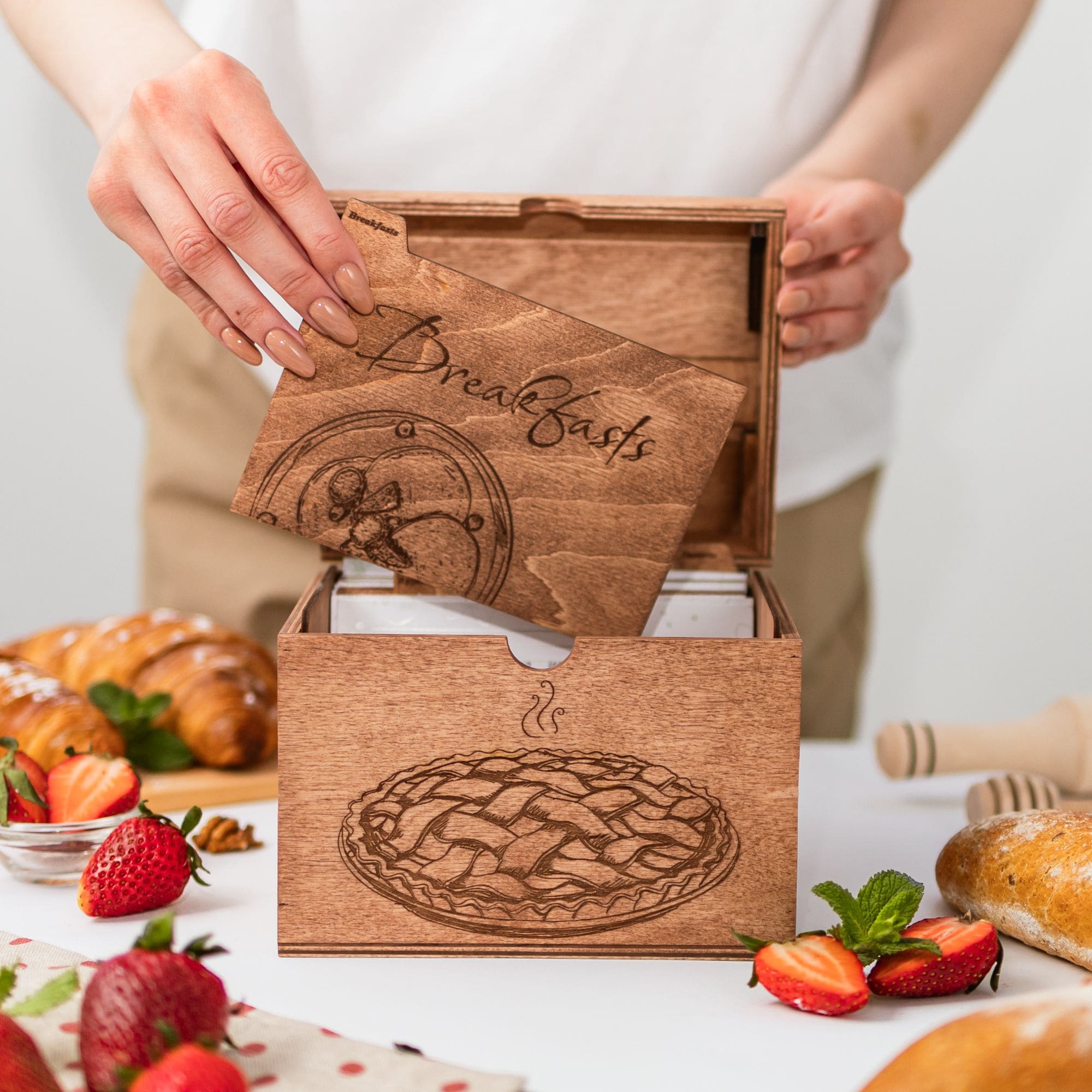 Woman inserting wooden divider card labeled Breakfast into recipe box.