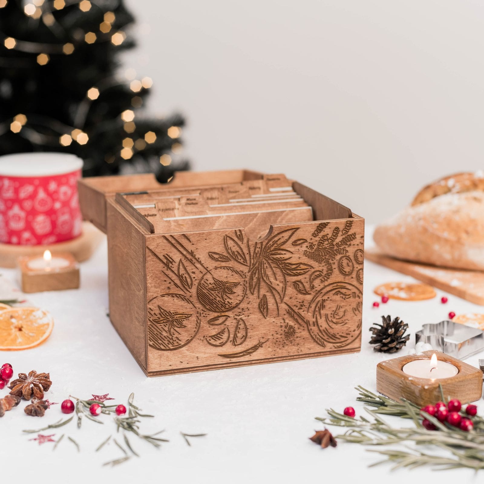 Open wooden recipe box with engraved design and recipe cards, holiday decor around