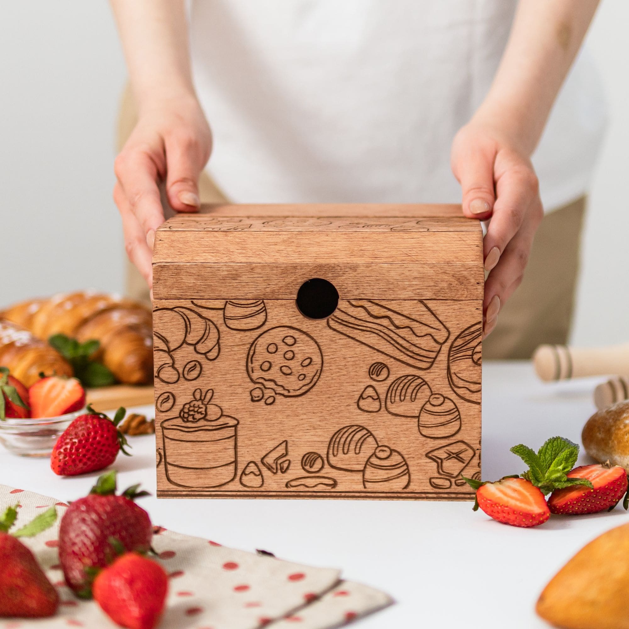 Closed wooden recipe box with engraved pastry illustrations on the table
