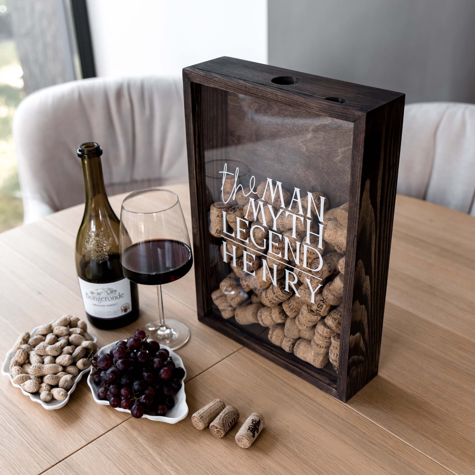A dark wooden wine cork display box with a clear front panel