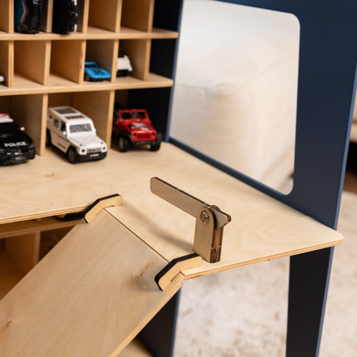 A close-up of a wooden children's play desk or ramp with a small metal latch