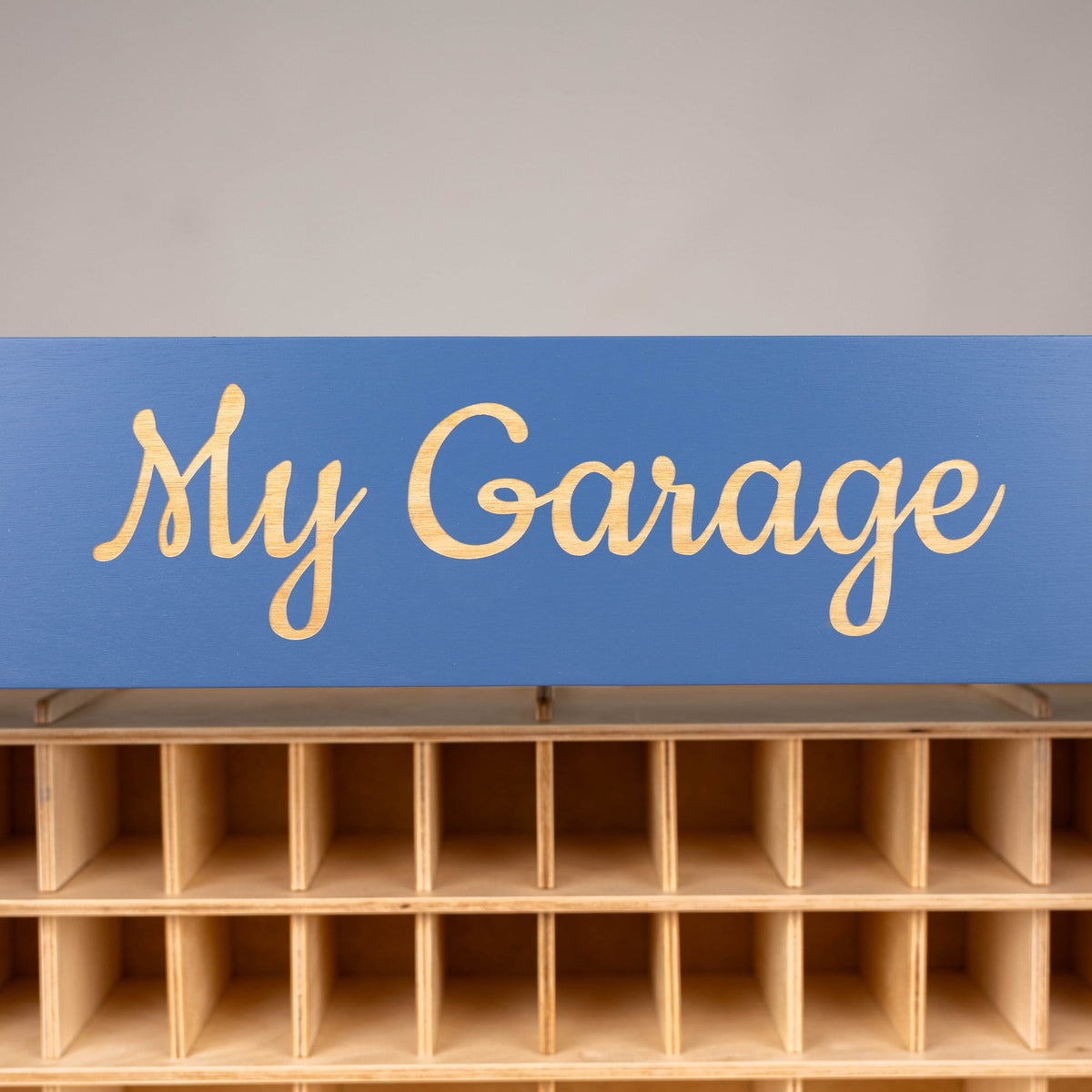 A blue rectangular sign with the words 'My Garage' in light wood lettering