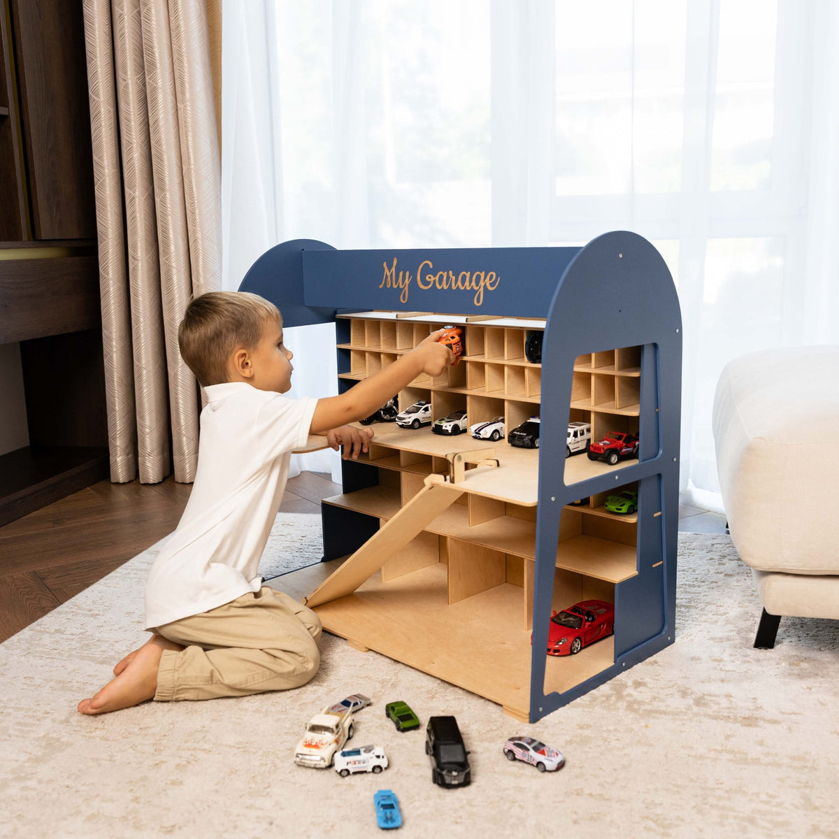 The garage is navy blue on the exterior with natural light wood shelves and ramps, and is decorated with small toy cars.