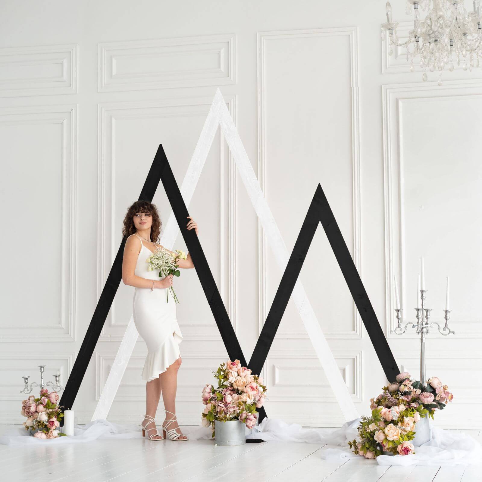 Bride in white dress posing near modern wedding arch decoration