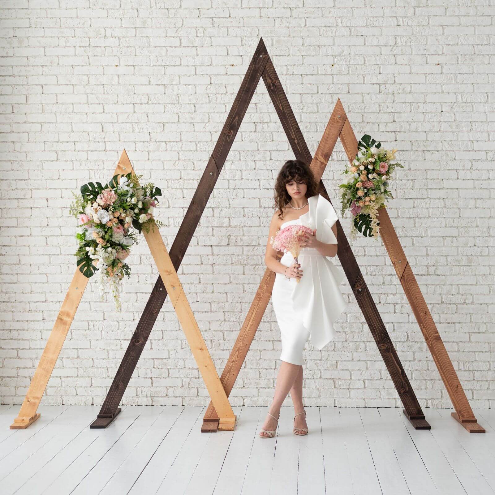 Wooden triangle arches decorated with flowers for rustic wedding.
