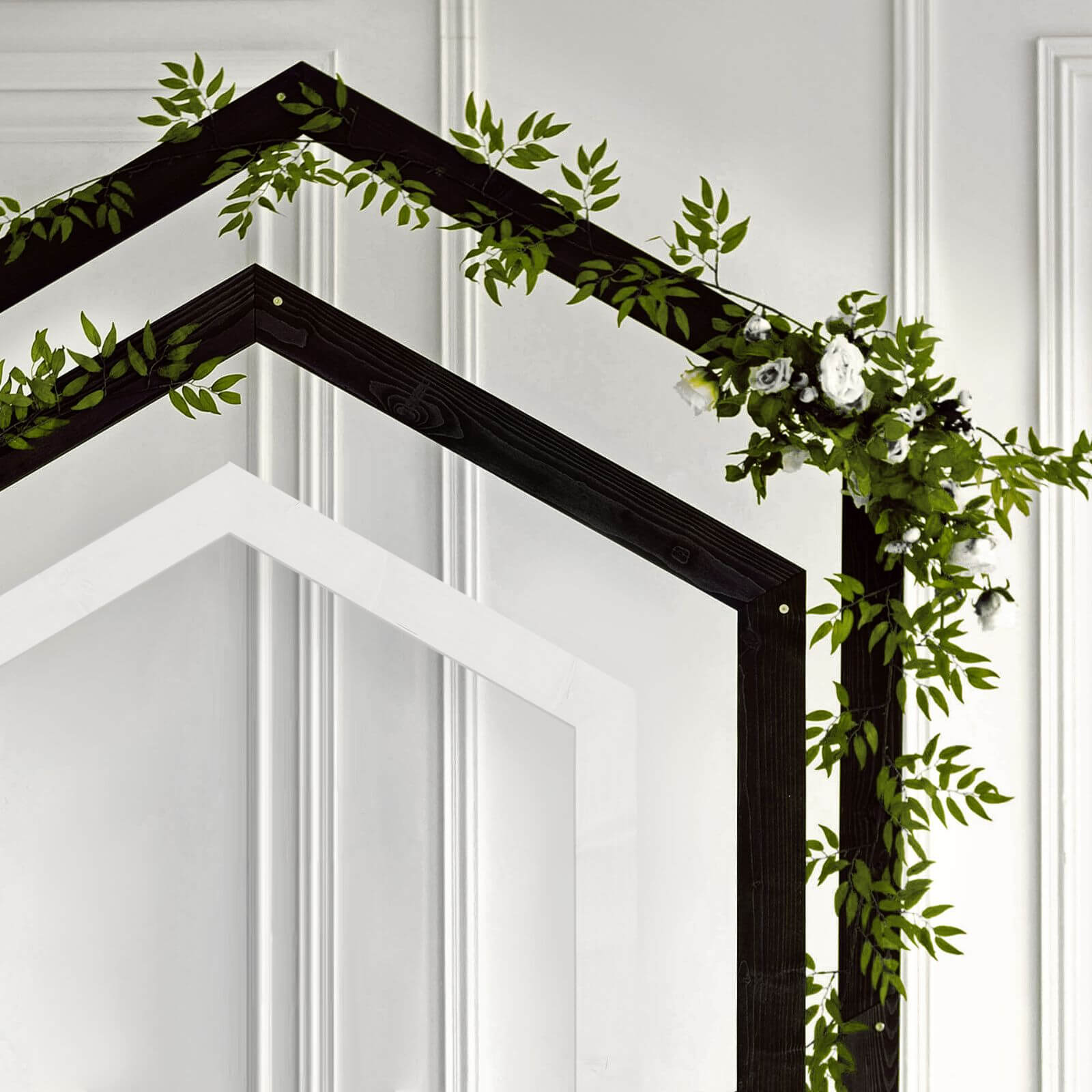 Black pentagon wedding arch decorated with white flowers and greenery.