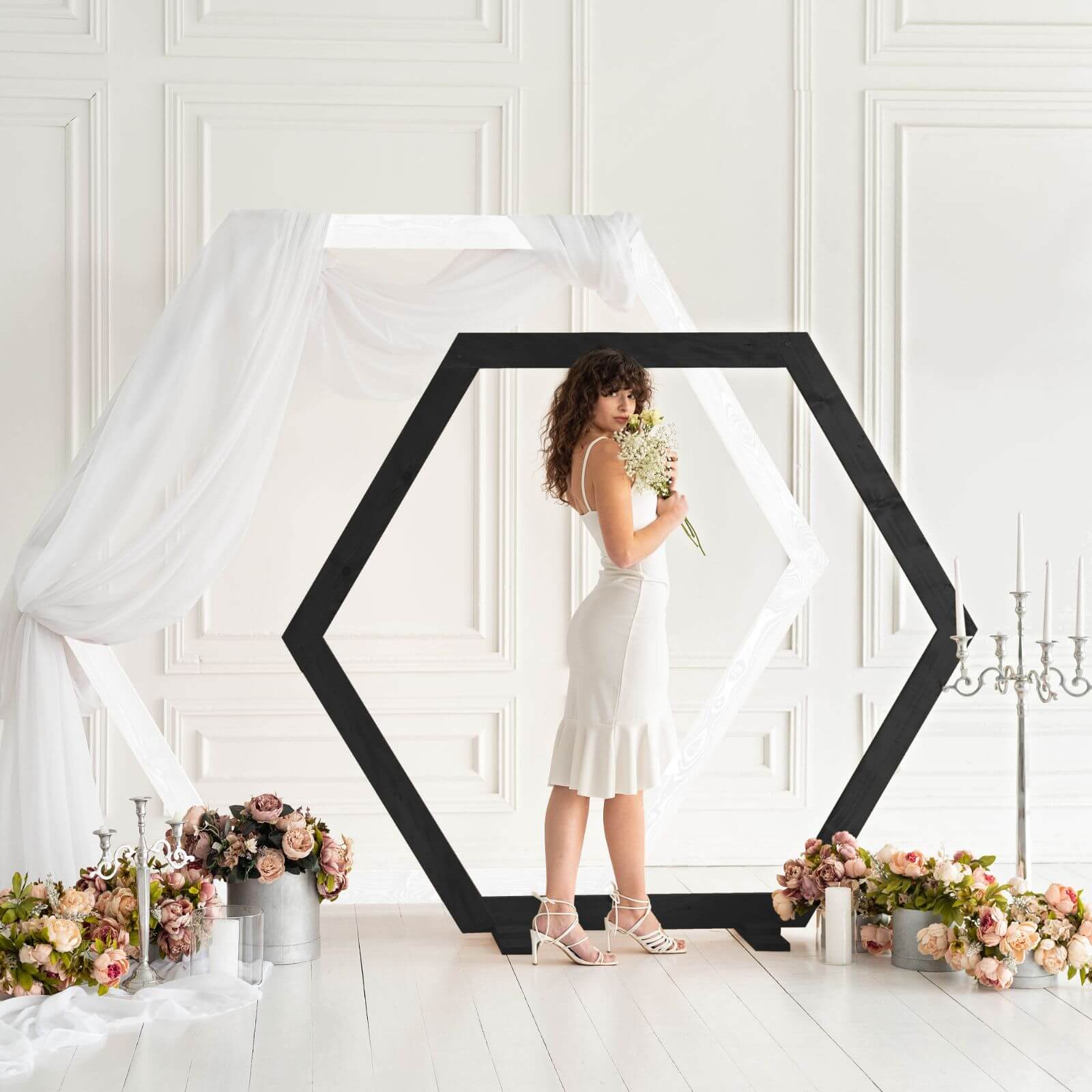 Bride standing in front of black hexagon wedding arch.