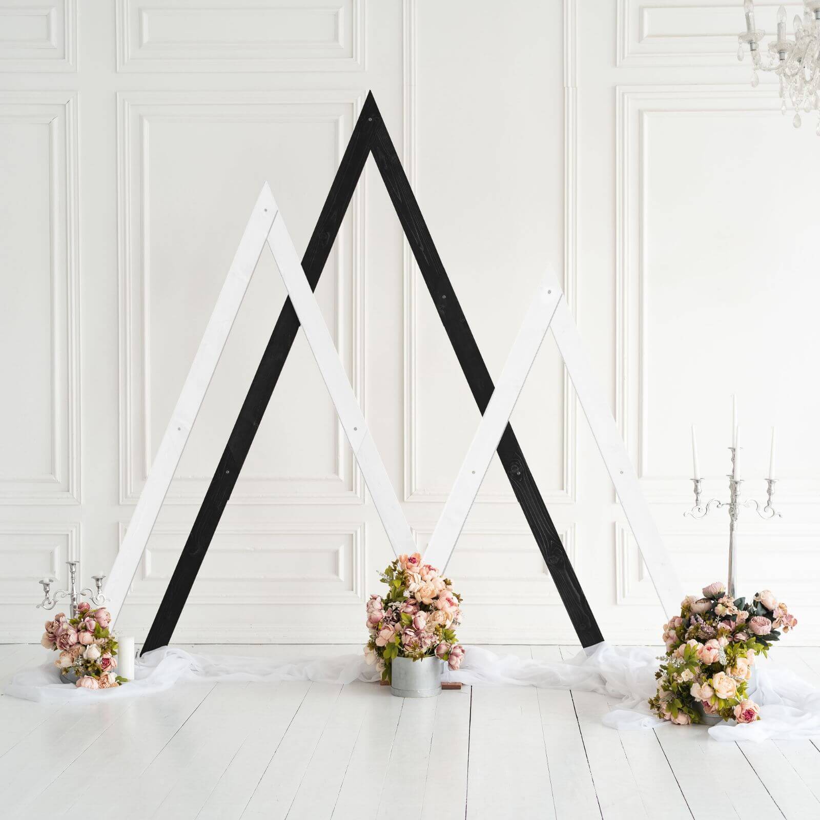 White and black triangle arches decorated with wedding flowers.