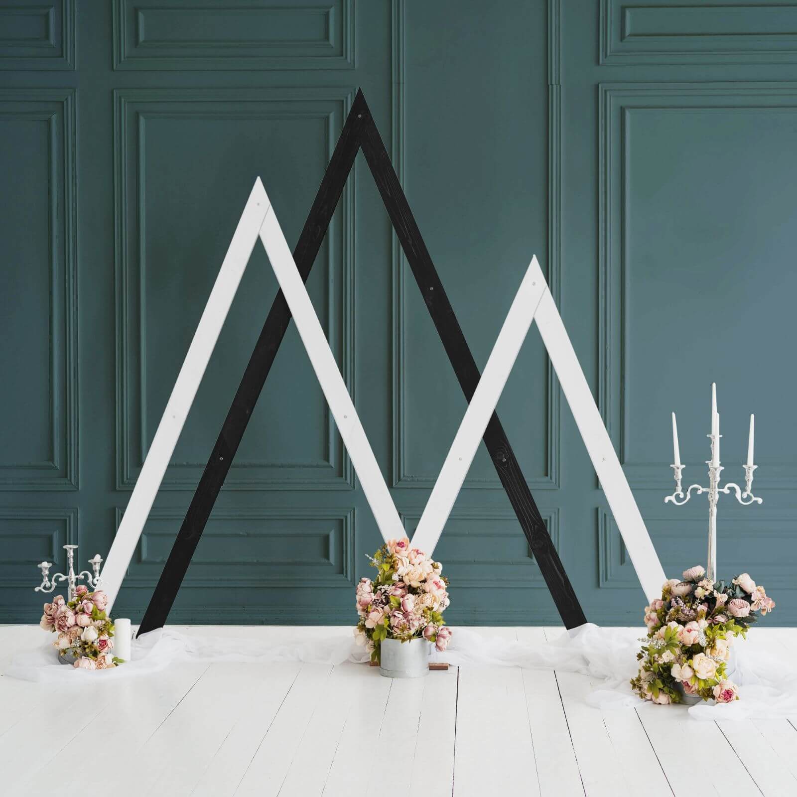 Modern triangle arches against dark wall with flower arrangements.