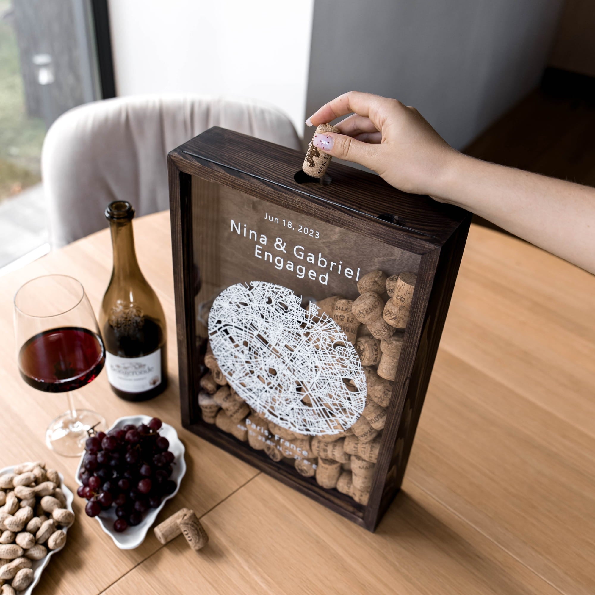 A wooden wine-cork box with a transparent front panel sits on a table.