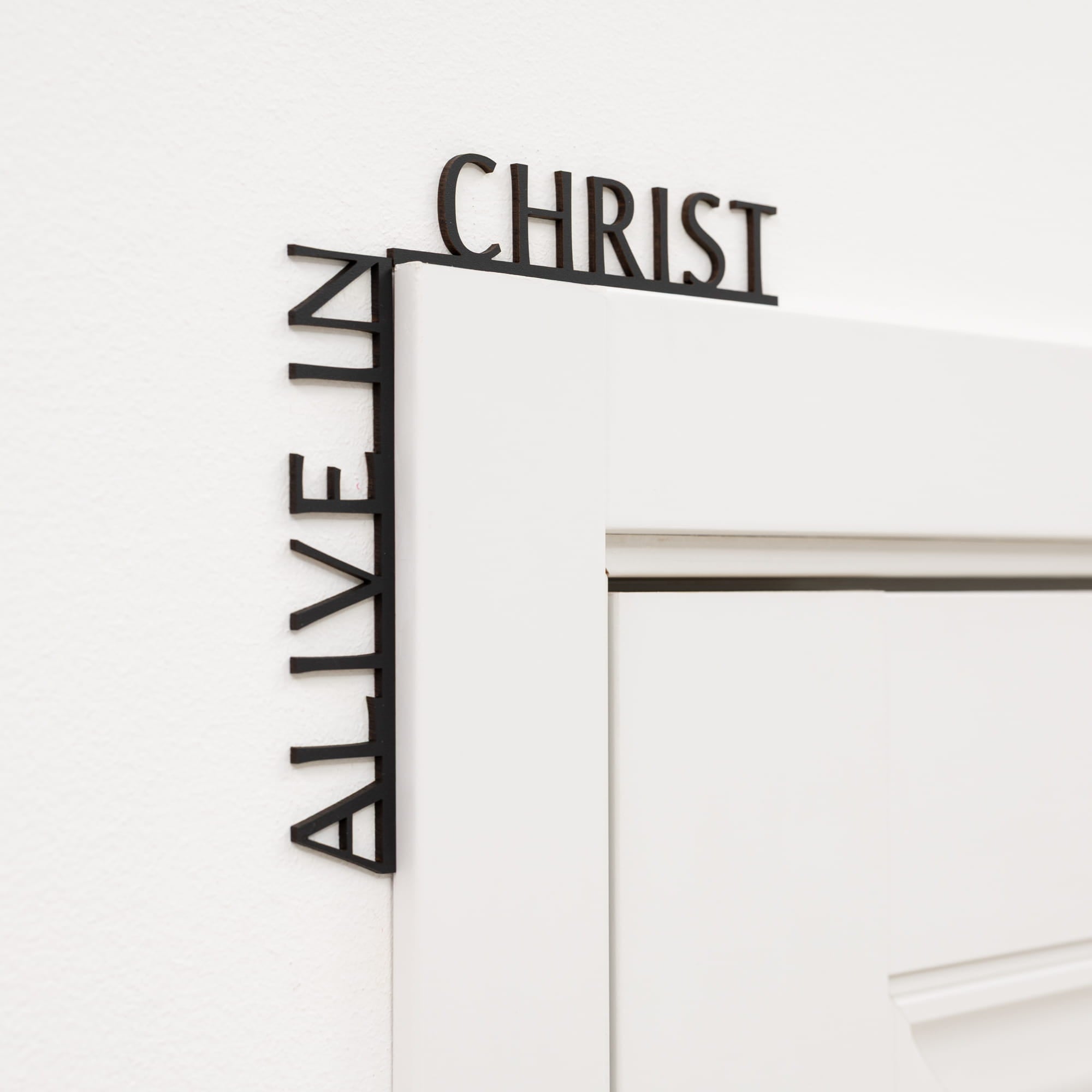 Decorative wall art with 'Alive in Christ' text on a white background