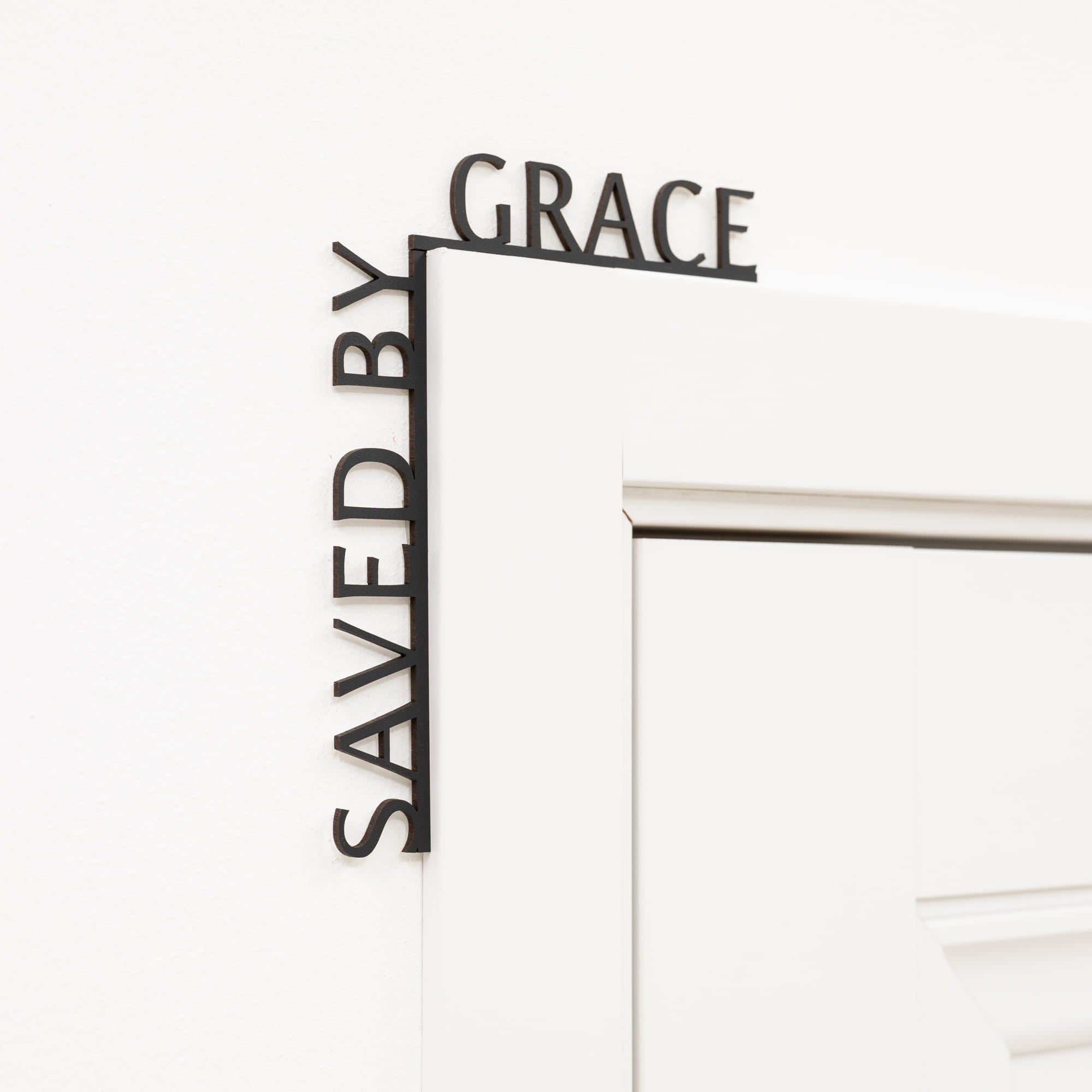 Decorative metal sign with 'Saved by Grace' text on a white background